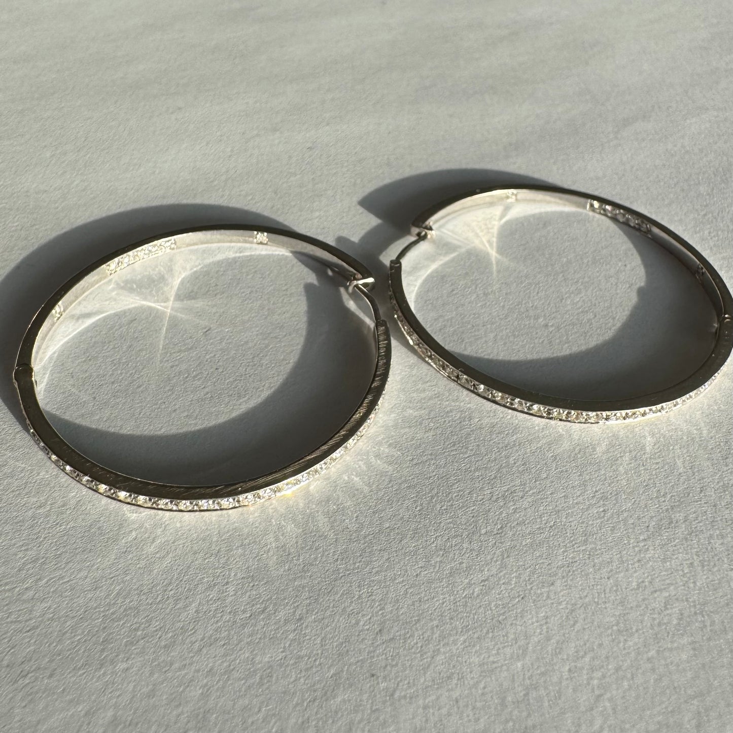 עגילי חישוק זהב 18 קראט, משובצים יהלומים לכל אורכם בחזית ובחלק הפנימי.