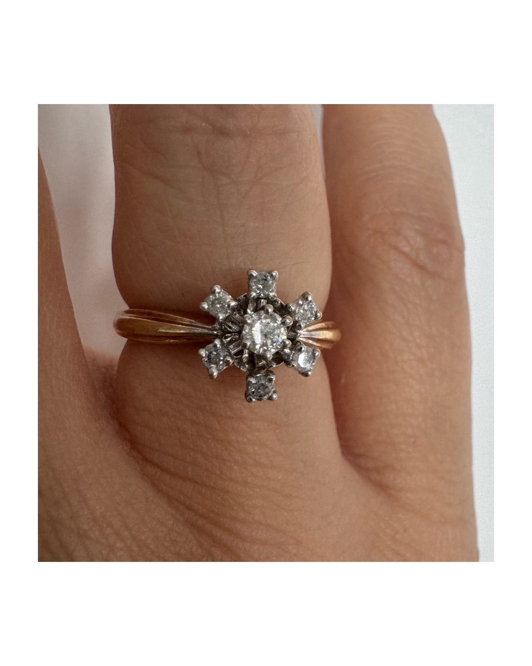 טבעת זהב 9 קראט משובצת יהלום מרכזי ויהלומים מסביב בעיצוב פרח קלאסי.
