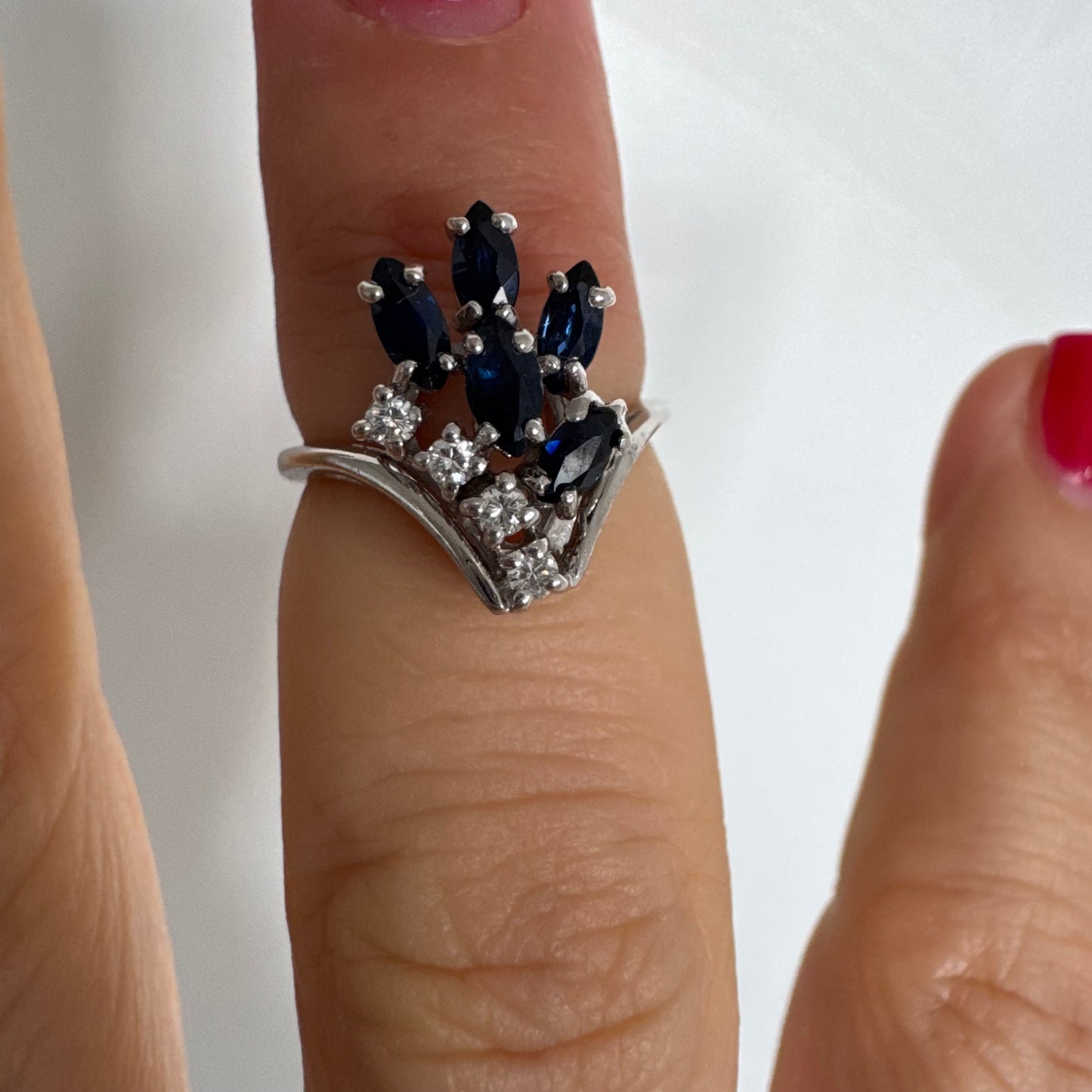 טבעת זהב לבן 14 קראט משובצת אבני ספיר כחולות בחיתוך מרקיזה ויהלומים, היוצרים מראה אלגנטי ודינמי.