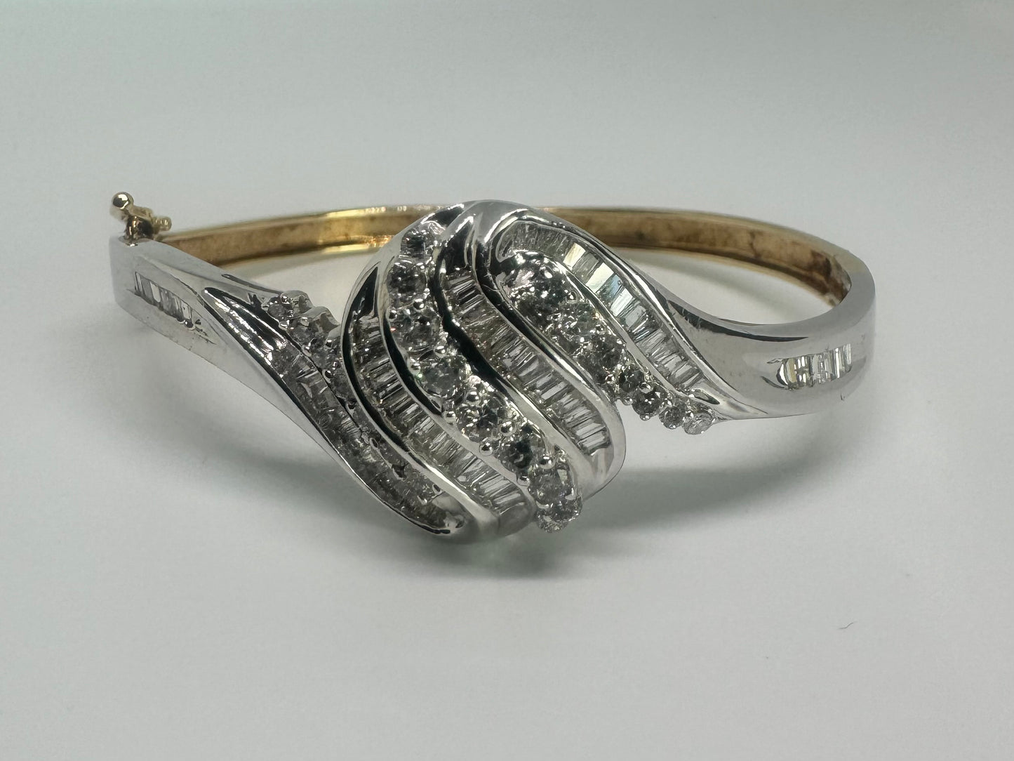 צמיד מרהיב מזהב לבן 14 קראט, בעיצוב גלים דינמי המשובץ בשיבוץ מרוכב של יהלומים עגולים ובחיתוך באגט.