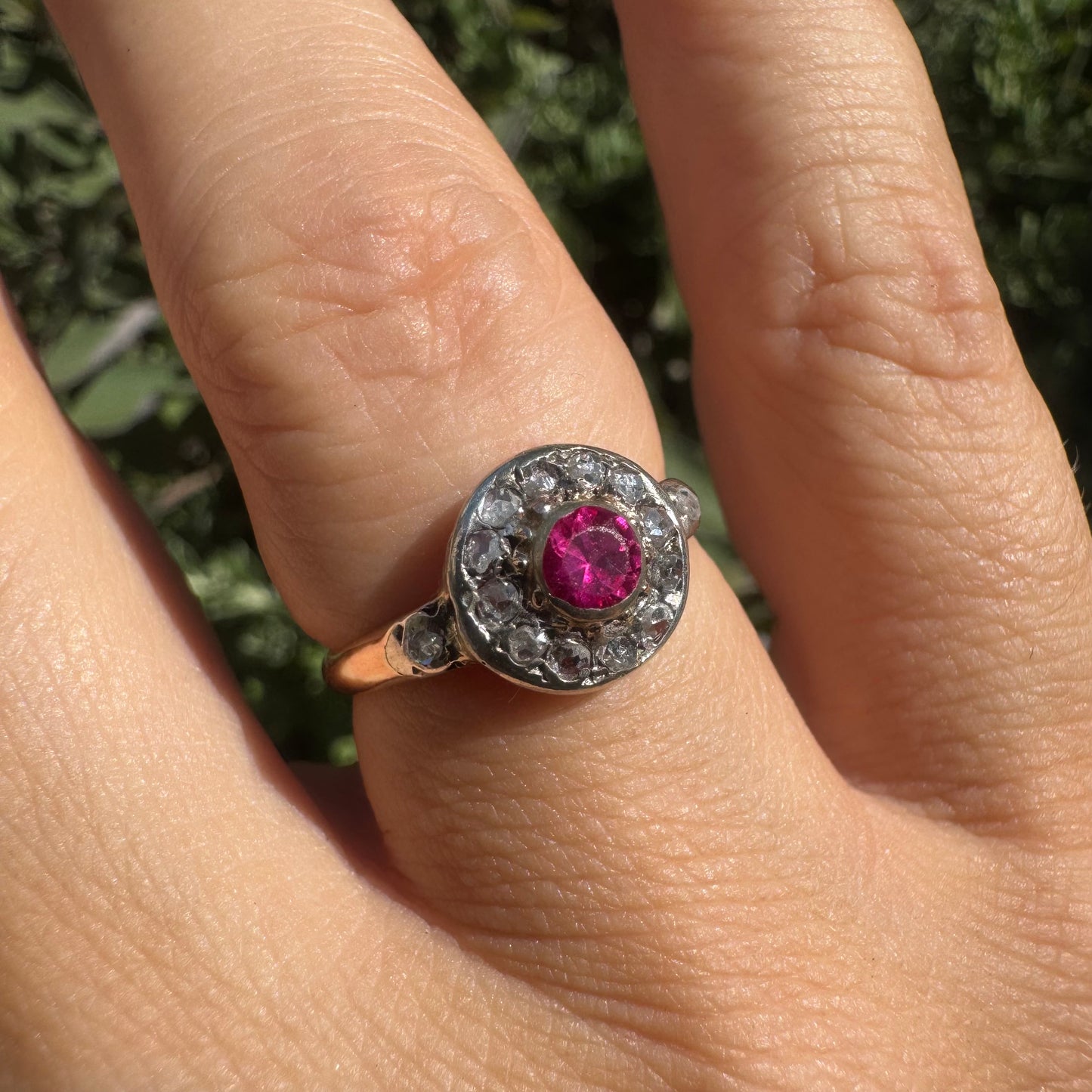 18K gold ring set with a round Ruby at the center, surrounded by a halo of old-cut Diamonds.