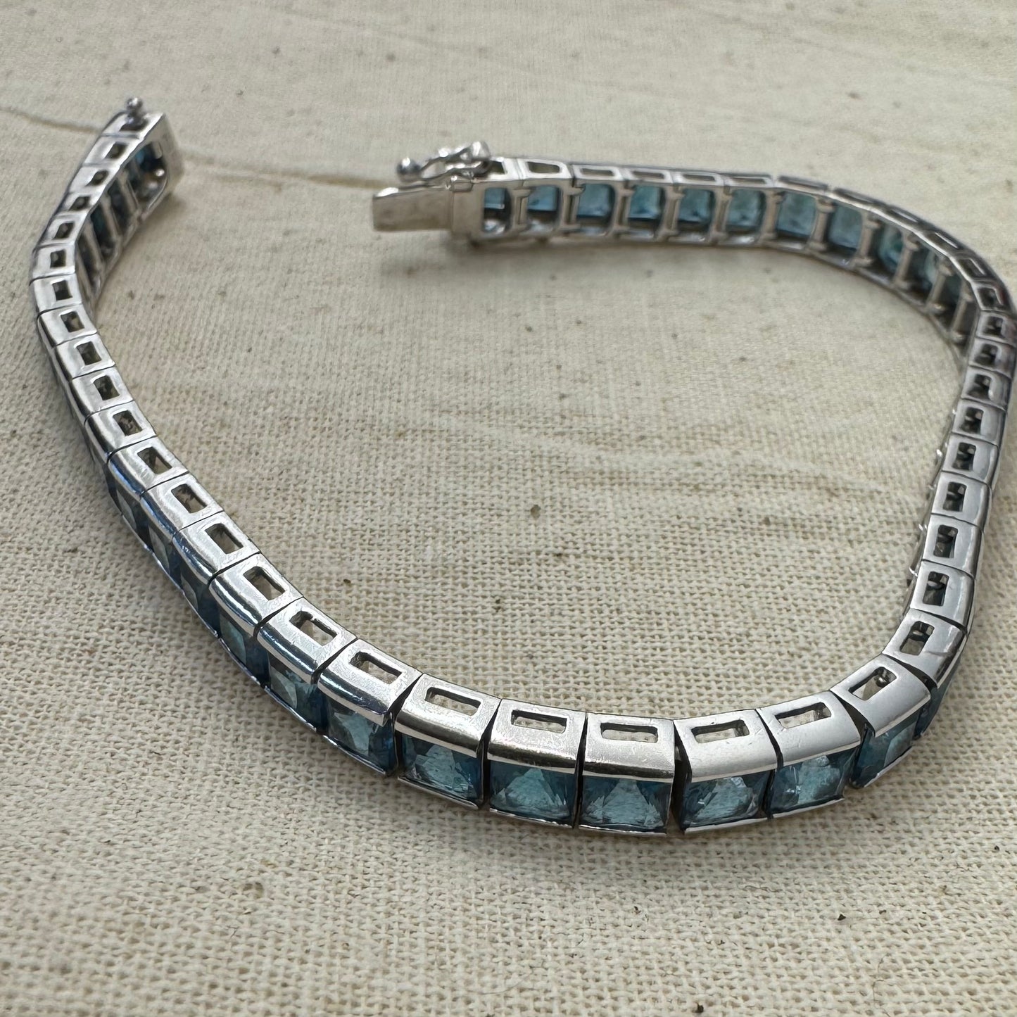 צמיד זהב לבן 18 קראט של המותג ה.שטרן משובץ אבני טופז כחולה&nbsp;בשיבוץ ערוץ חלק וקלאסי – פריט נצחי עם טאץ’ מודרני