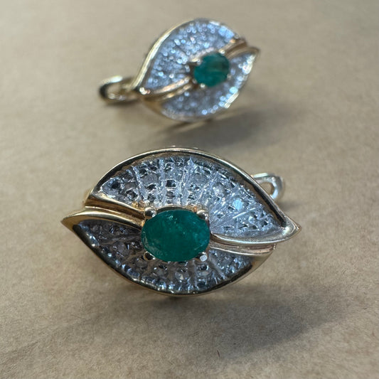 עגילים צמודים לאוזן, זהב צהוב 14 קראט, משובצים אמרלד במרכז, וסביבן פיתוחים משובצים יהלומים, שמעניקים מראה של ניצוץ רך ואלגנטי