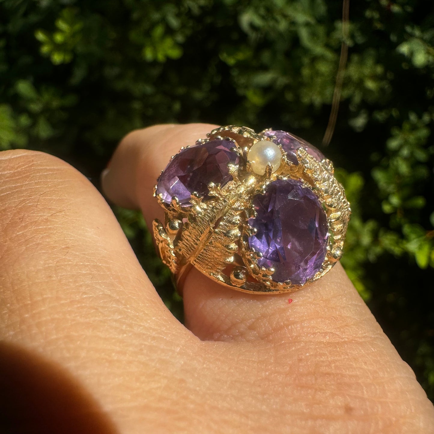 14K gold ring set with four glowing Amethyst stones encircling a delicate central Pearl.