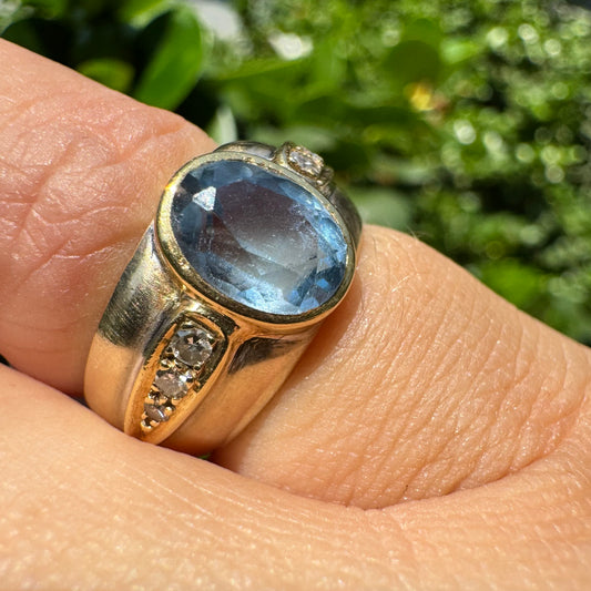 14K gold ring set with a luminous Blue Topaz at its center, accented by delicate side Diamonds