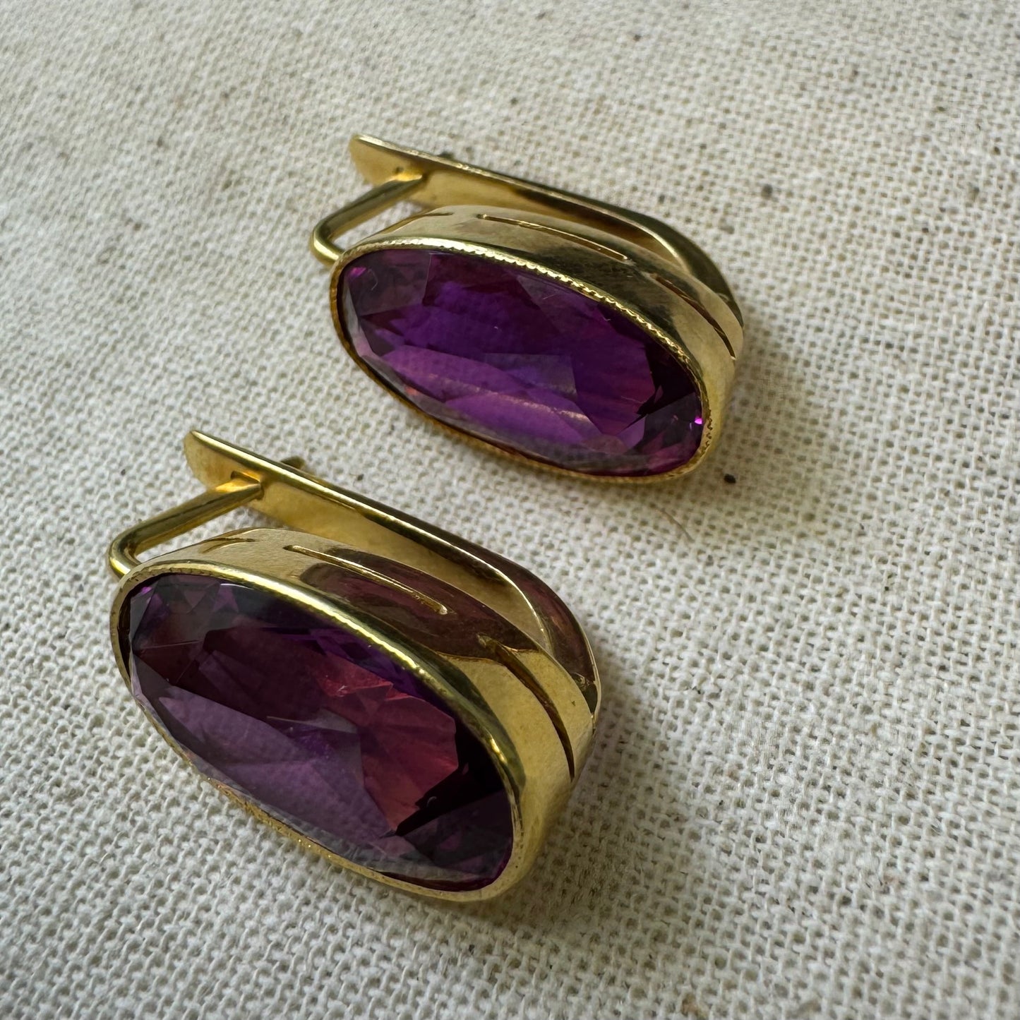 עגילי זהב צהוב 18 קראט, תלויים קצרים, משובצים באבני אמטיסט סגולות בחיתוך אובלי עמוק.