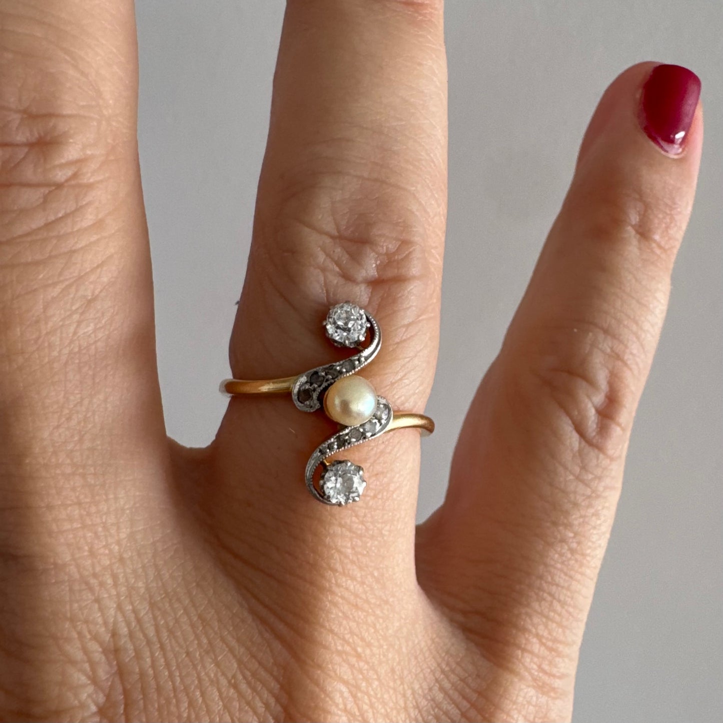 טבעת זהב 18 קראט בעיצוב וינטג׳ קלאסי, משובצת בשני יהלומים בחיתוך עתיק ובפנינה טבעית במרכז.