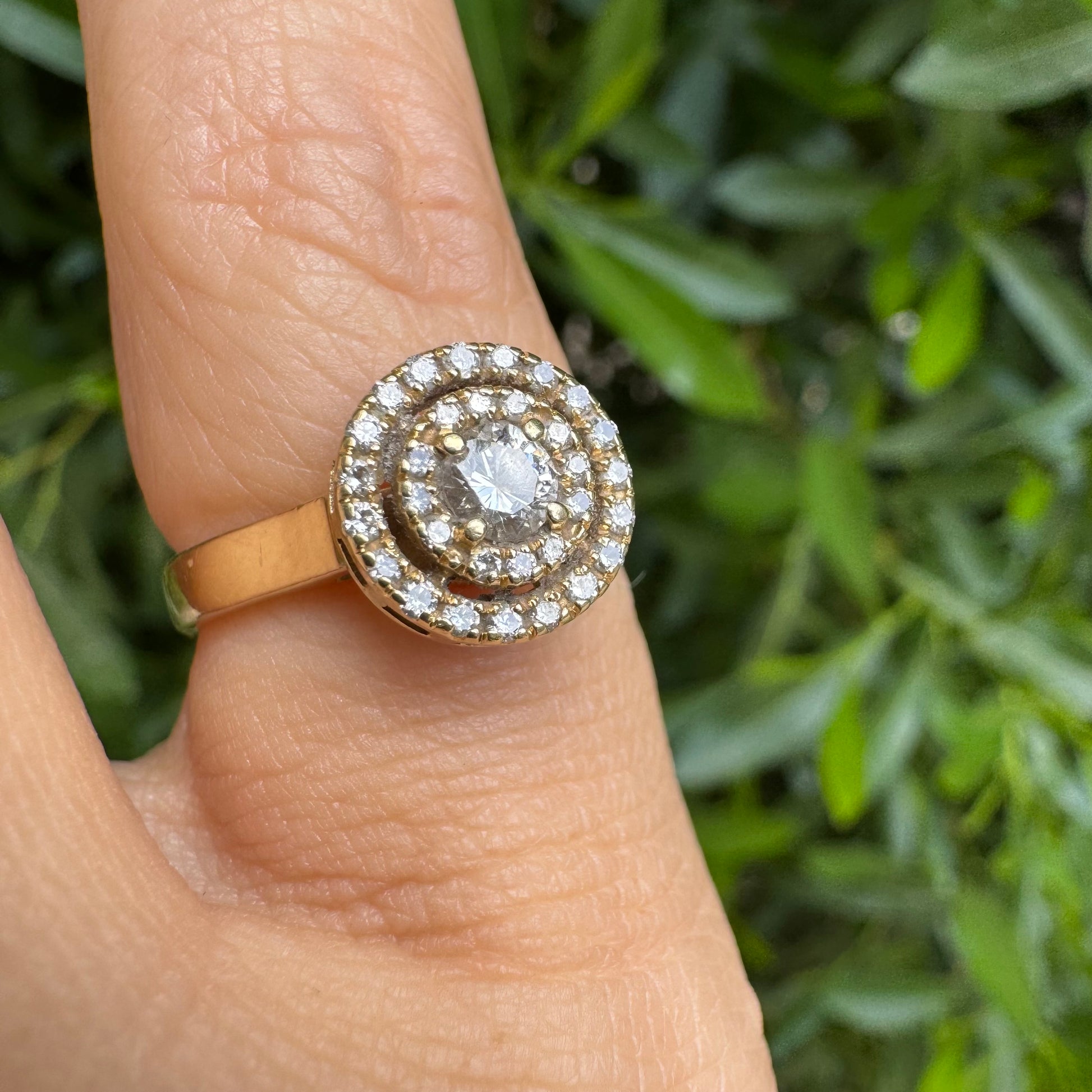 טבעת זהב צהוב 14 קראט משובצת יהלום מרכזי עגול מוקף בשתי שכבות של יהלומים קטנים יותר, המעצימות את הברק והנוכחות של הטבעת