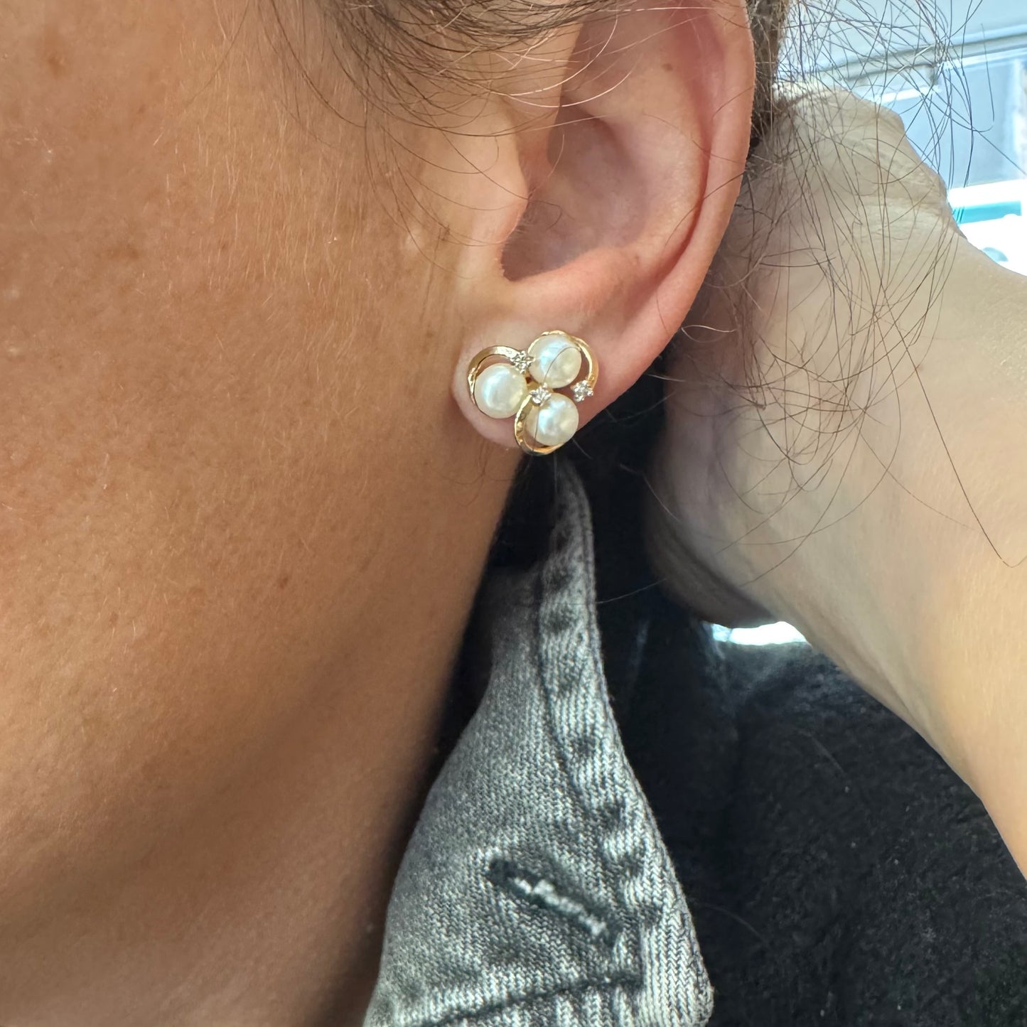 עגילי זהב 10 קראט בעיצוב פרחוני עדין, משובצים שלוש פנינים עגולות בגוון קרמי טבעי וביניהן יהלומים.