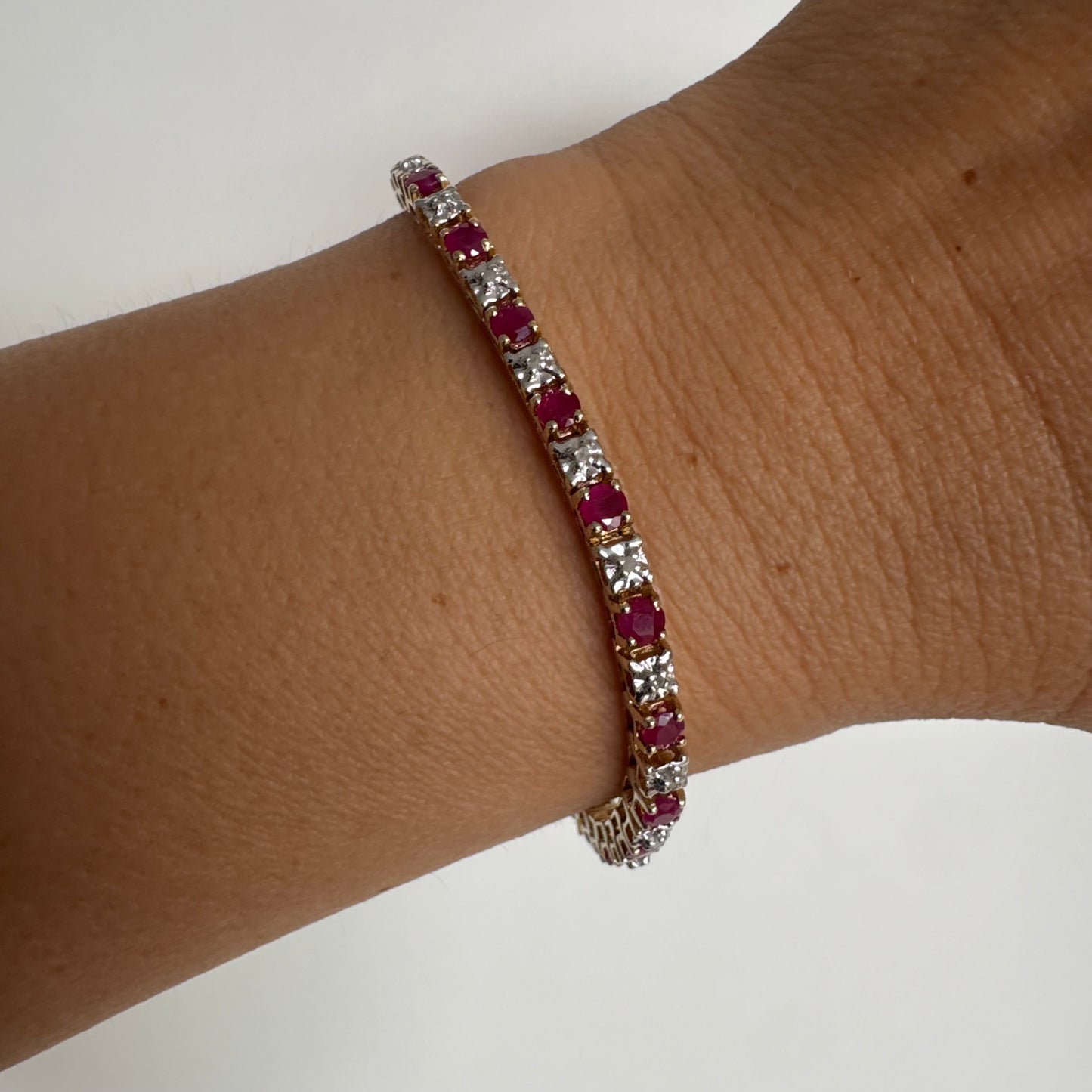 צמיד זהב צהוב 10 קראט משובץ אבני רובי בגוון אדום עמוק וביניהן יהלומים לבנים מנצנצים.