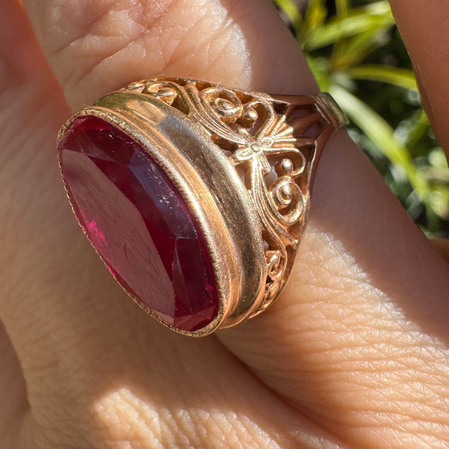 14K gold ring crowned with a vivid oval-cut Ruby, framed in an ornate bezel and accented by intricate filigree details