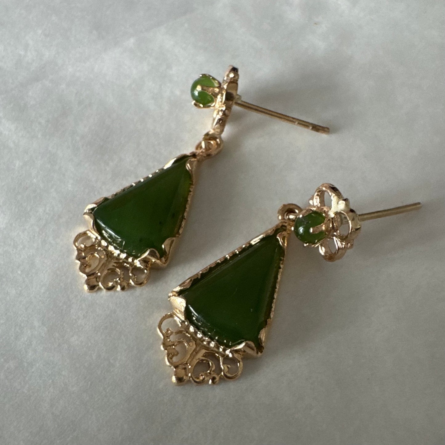 עגילי זהב צהוב 14 קראט משובצים אבני ג׳ייד ירוקות בגוון עמוק בחיתוך משולש.