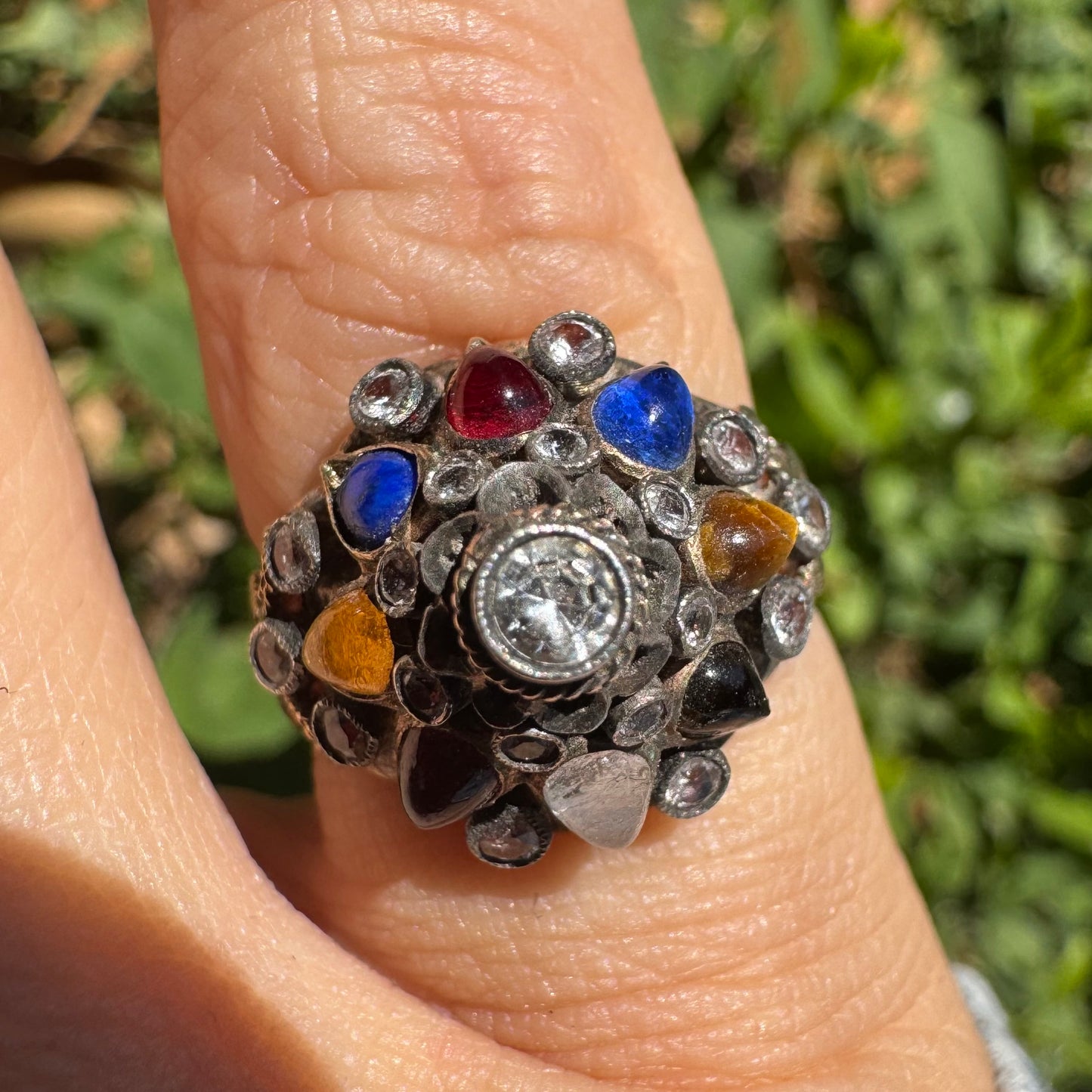 14K gold ring set with a central transparent gemstone surrounded by a vibrant mosaic of colorful gemstones -set in an ornate, handcrafted design