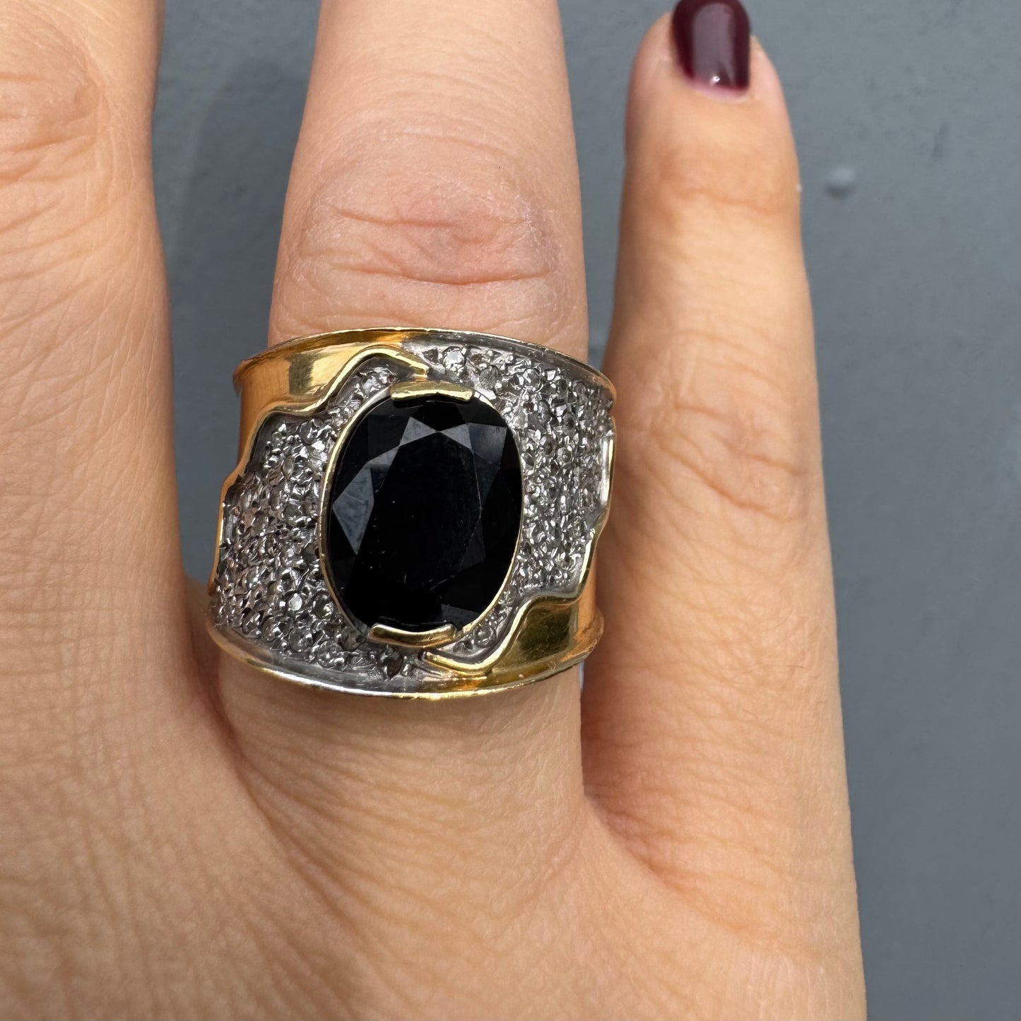 טבעת זהב צהוב 18 קראט משובצת יהלומים ואבן ספיר בצבע כחול כהה במרכז בעלת עיצוב דרמטי ואלגנטי בסגנון וינטג׳-יוקרתי