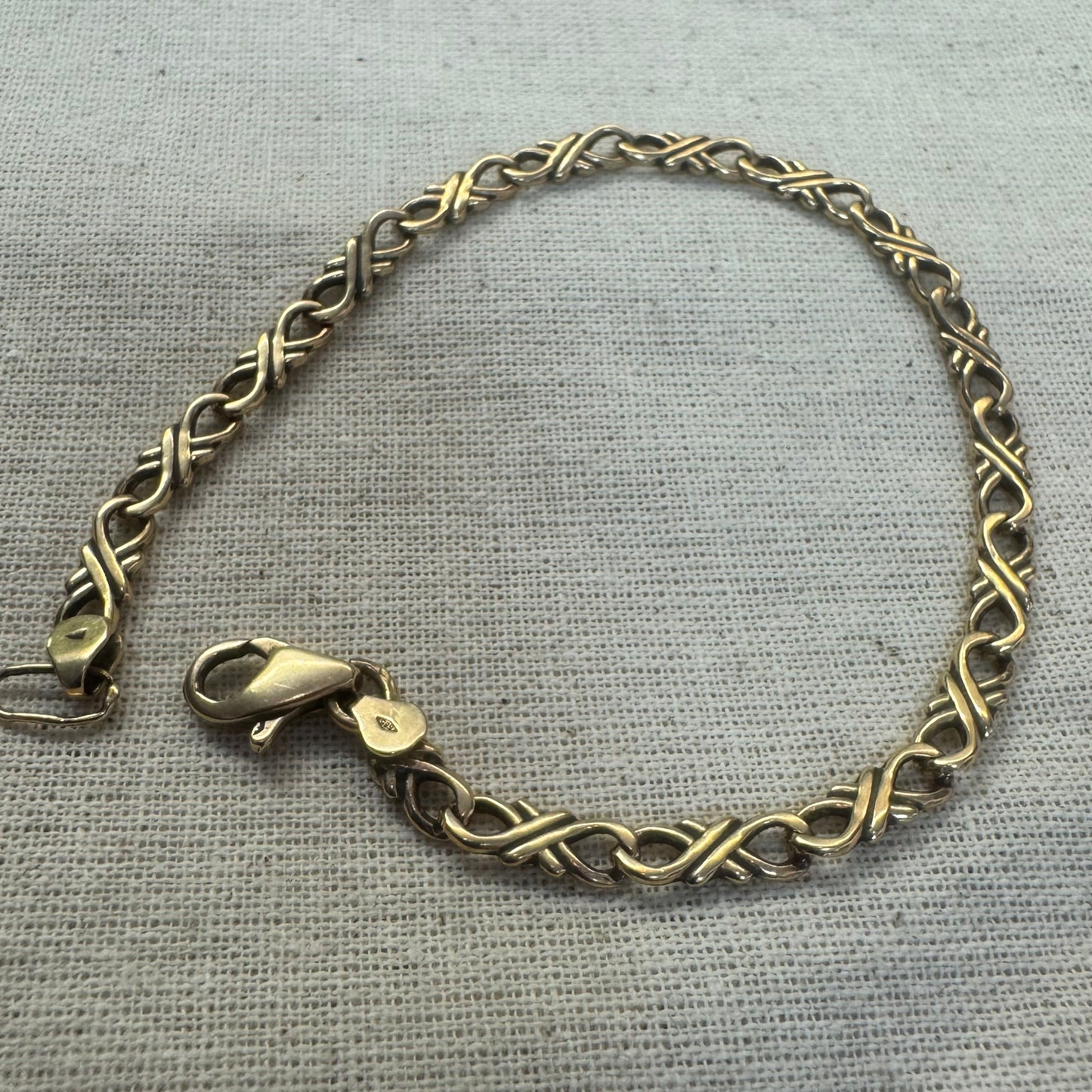 צמיד זהב צהוב 14 קראט עם חוליות שזורות בעיצוב שזירה ופיתול, וסוגר מסוג לובסטר.