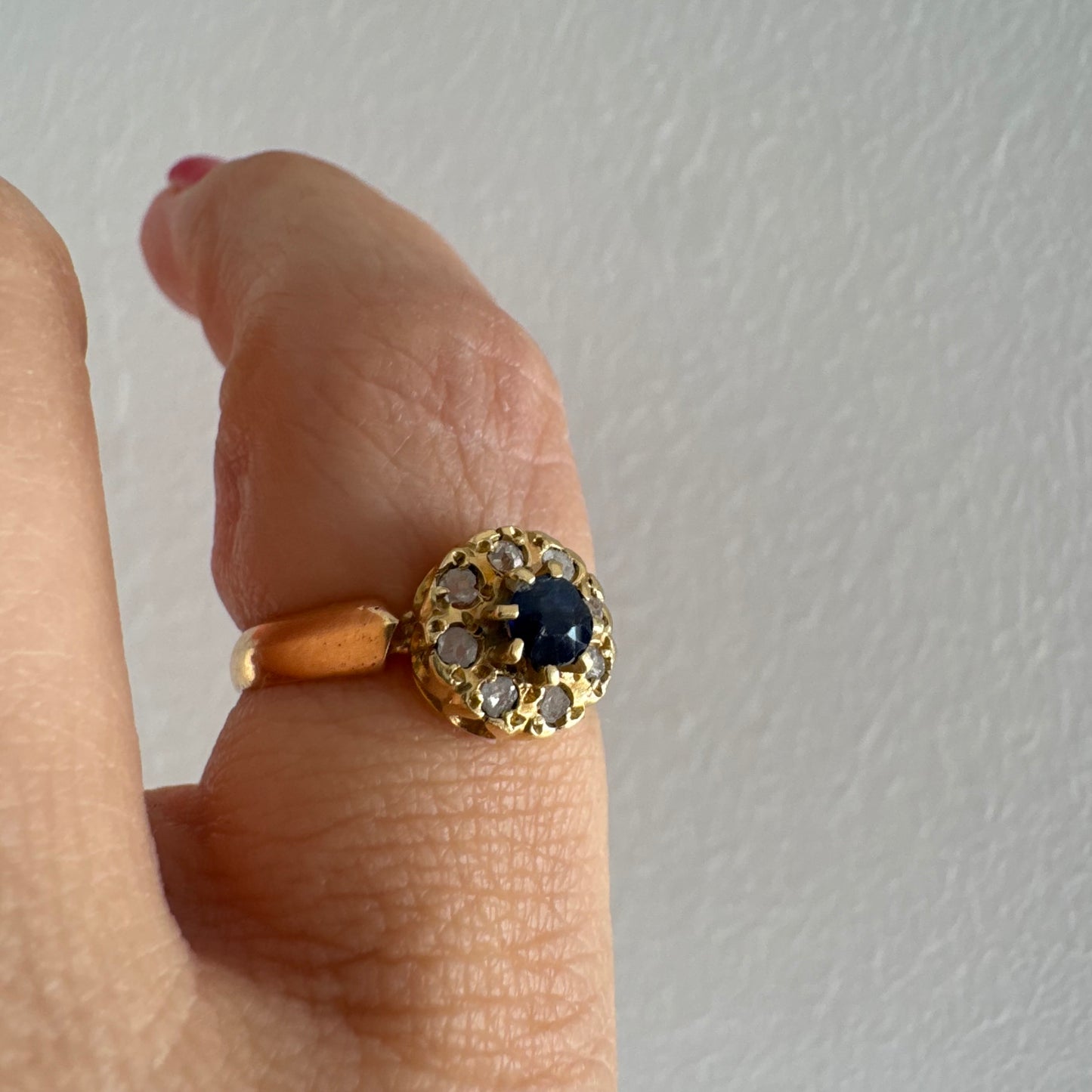 טבעת זהב 14 קראט משובצת ספיר מרכזי מוקף הילה של יהלומים בחיתוך עגול.