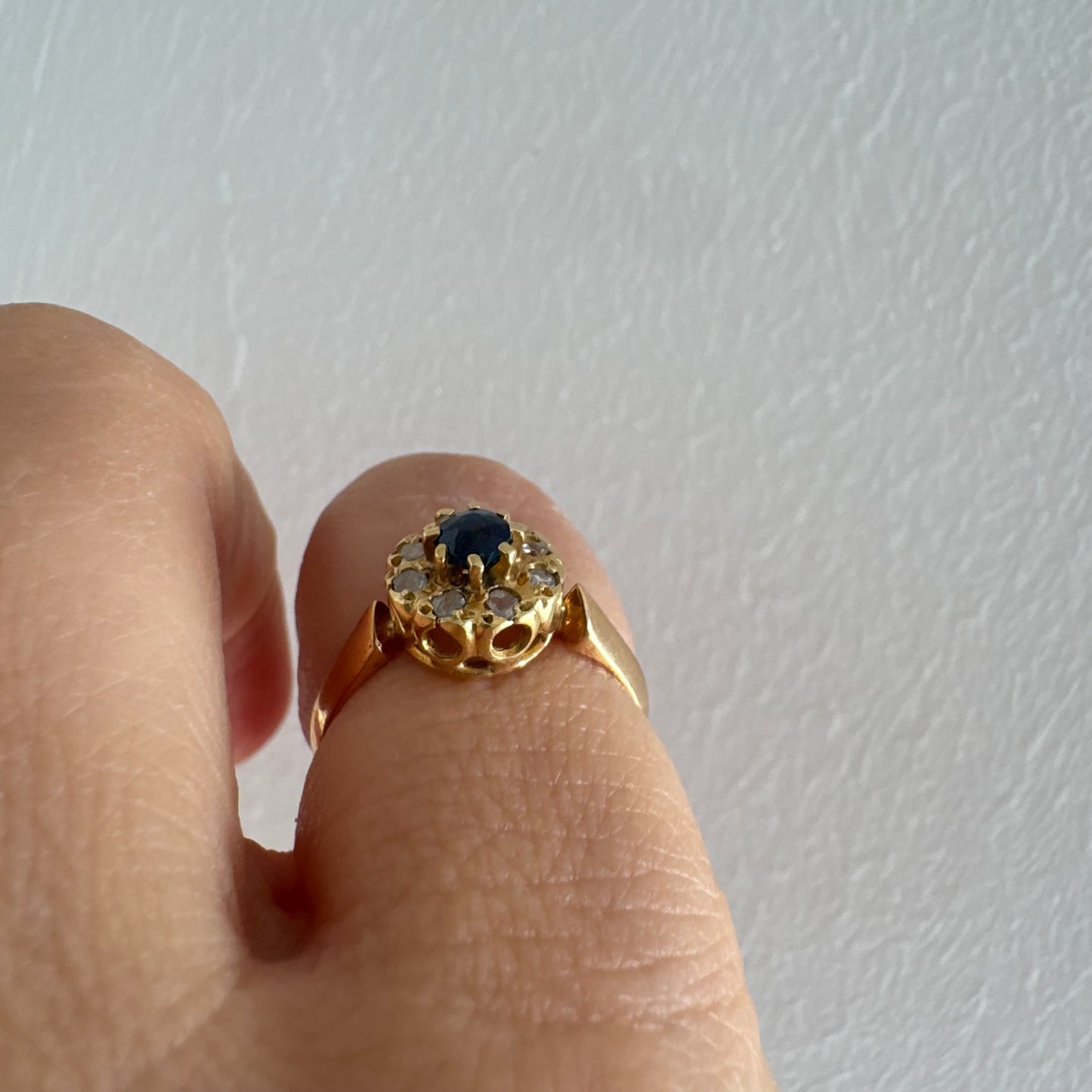 טבעת זהב 14 קראט משובצת ספיר מרכזי מוקף הילה של יהלומים בחיתוך עגול.