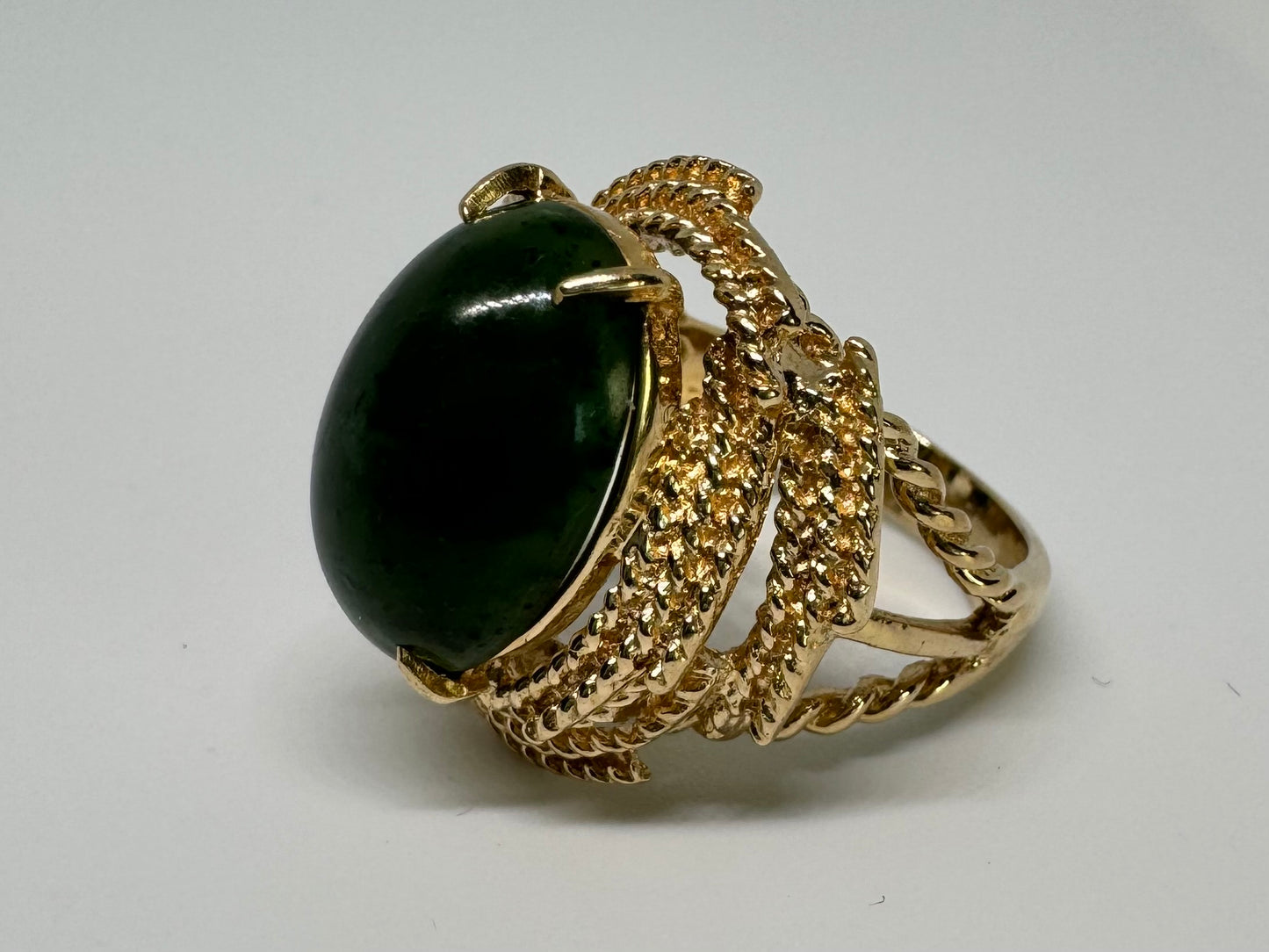 14K gold ring set with a deep green Jade set in a textured gold frame.