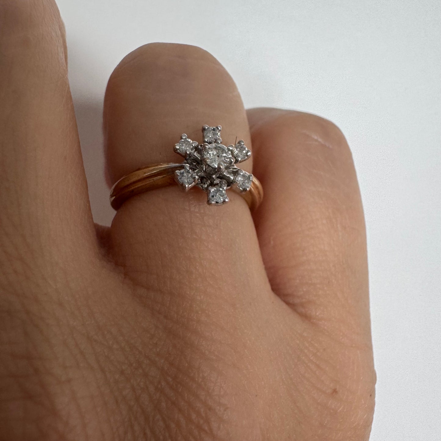 טבעת זהב 9 קראט משובצת יהלום מרכזי ויהלומים מסביב בעיצוב פרח קלאסי.