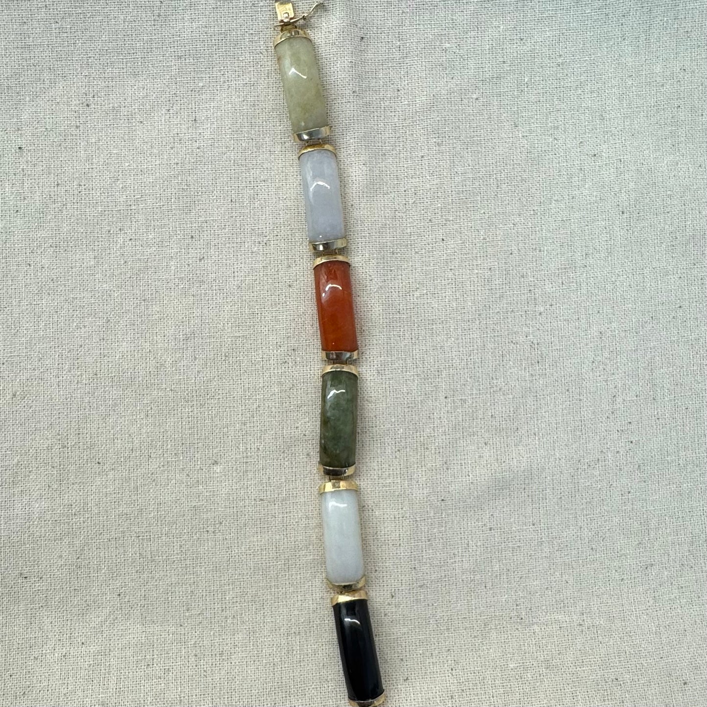 צמיד זהב צהוב 14 קראט עשוי מקטעי ג’ייד (jade) בשלושה גוונים – ירקרק, לבן ואדום – בשיבוץ זהב.