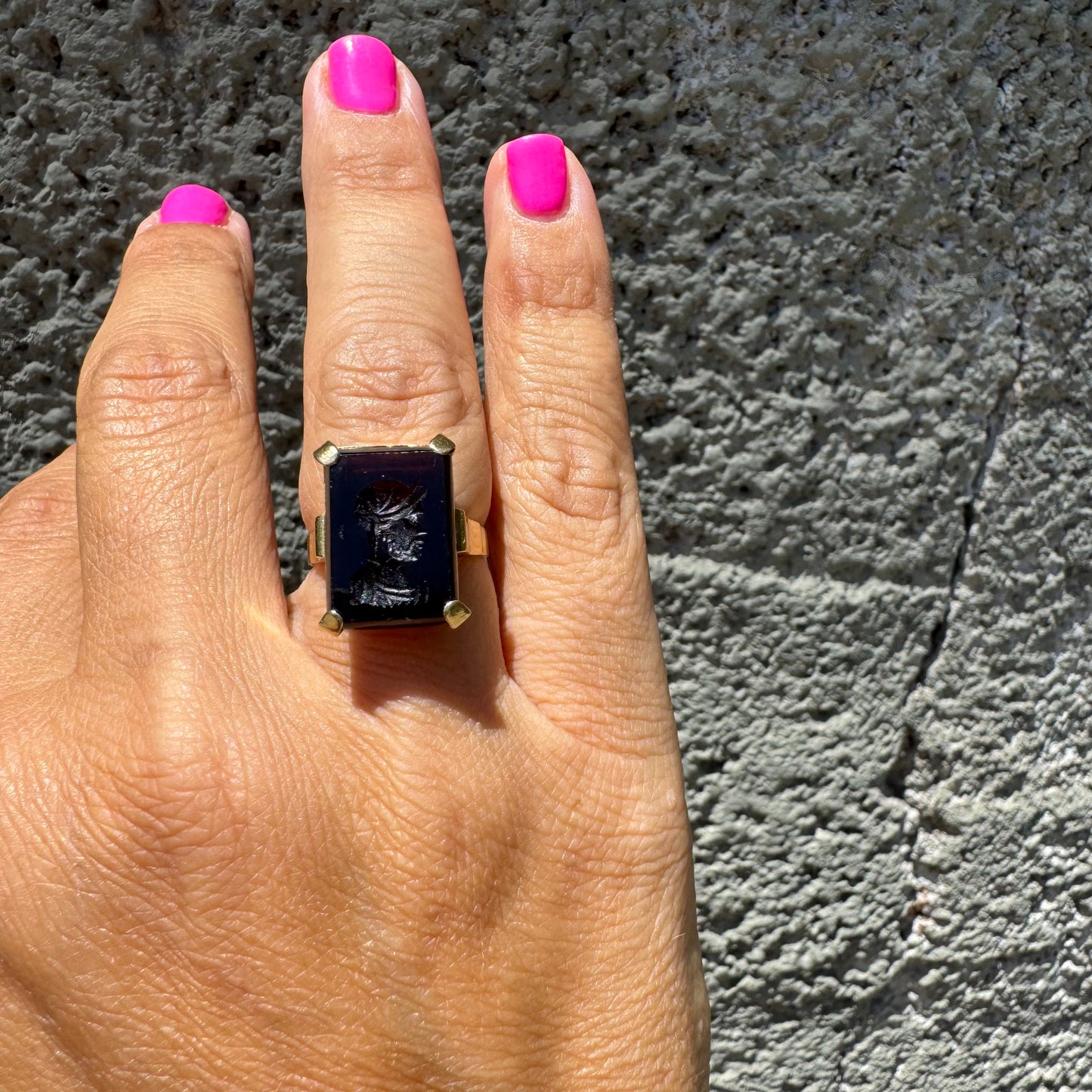 18K gold ring set with a carved dark stone featuring a classical warrior profile.