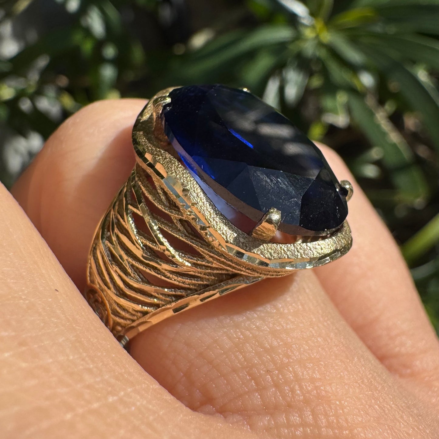 14K gold ring set with a deep navy-blue oval Sapphire in a dramatic openwork setting