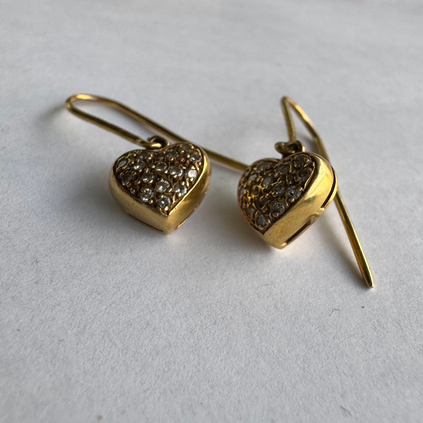 עגילי זהב צהוב 18 קראט תלויים בצורת לב, משובצים יהלומים קטנים המוסיפים ברק עדין ונוכחות אלגנטית.