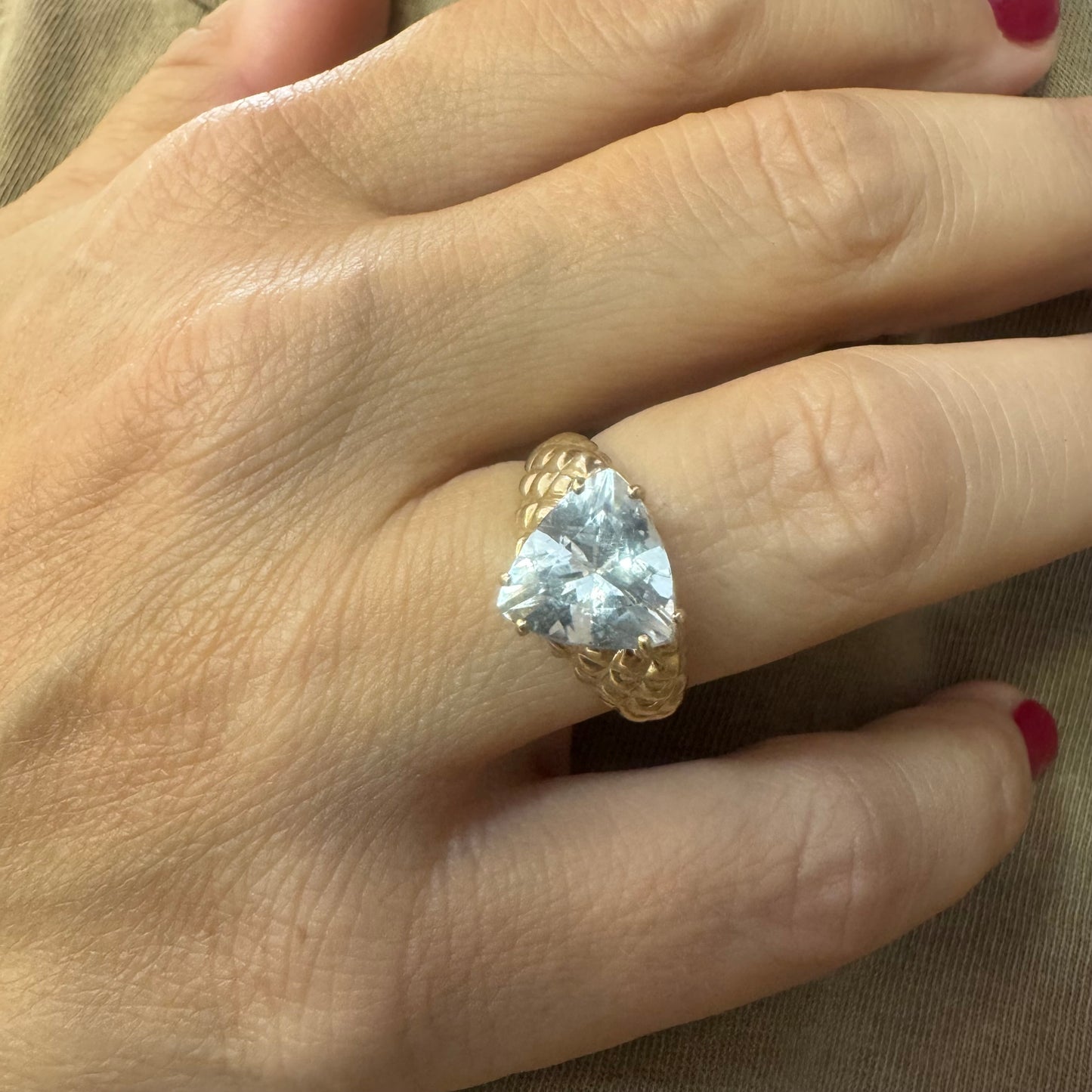 10K gold ring featuring a large, triangular-cut transparent gemstone set in a bold textured band