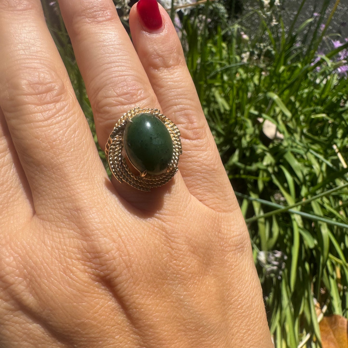 14K gold ring set with a deep green Jade set in a textured gold frame.
