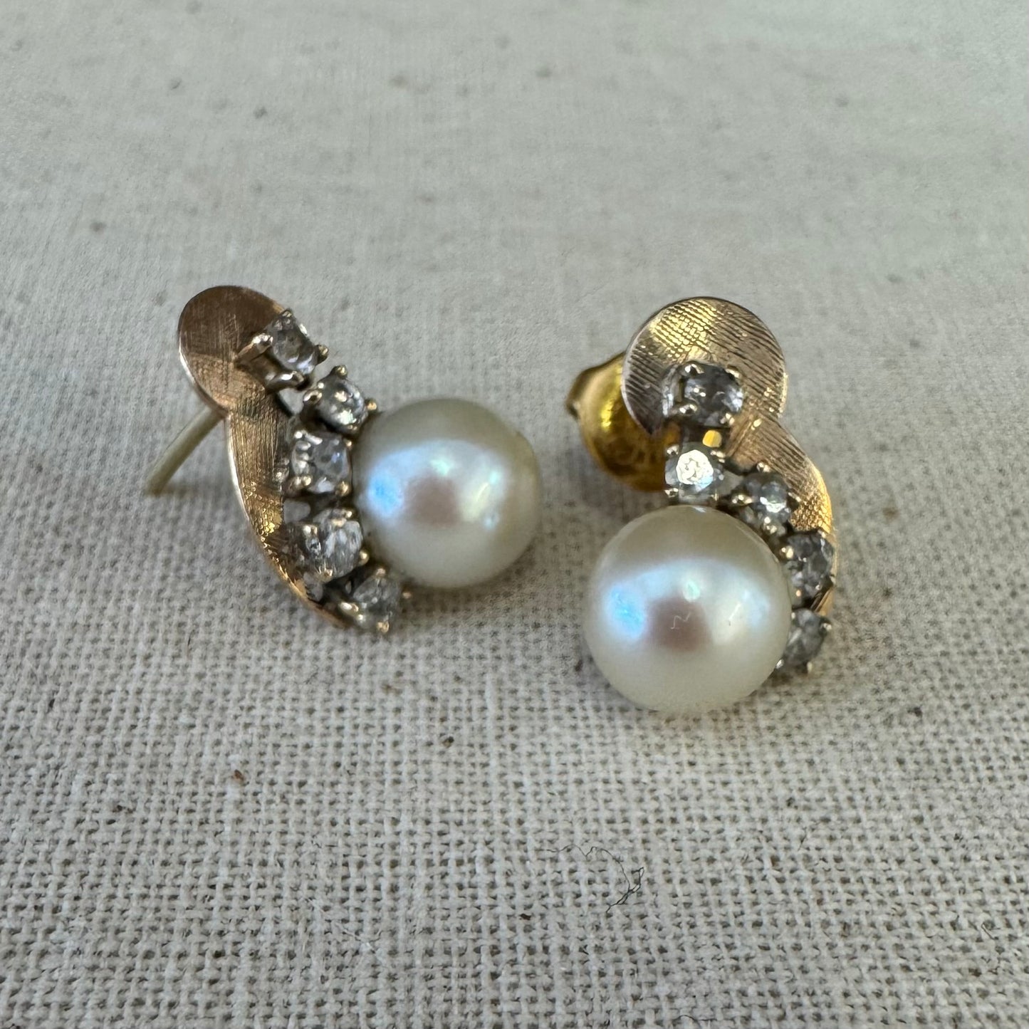 עגילי זהב צהוב 14 קראט, צמודים לאוזן, עשויים זהב בגימור טקסטורלי ומשובצים פנינה עגולה ובשורת יהלומים קטנים בחיתוך עתיק.