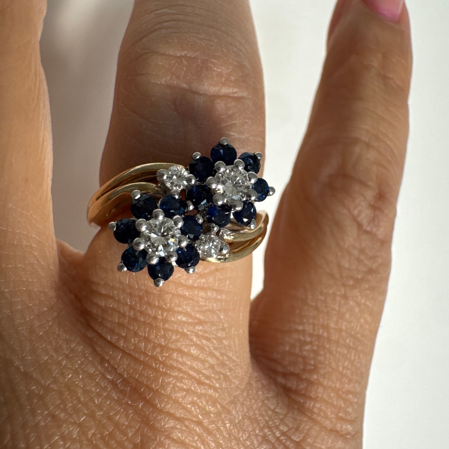 טבעת זהב צהוב 14 קראט משובצת אבני ספיר ויהלומים בעיצוב פרחים כפול.