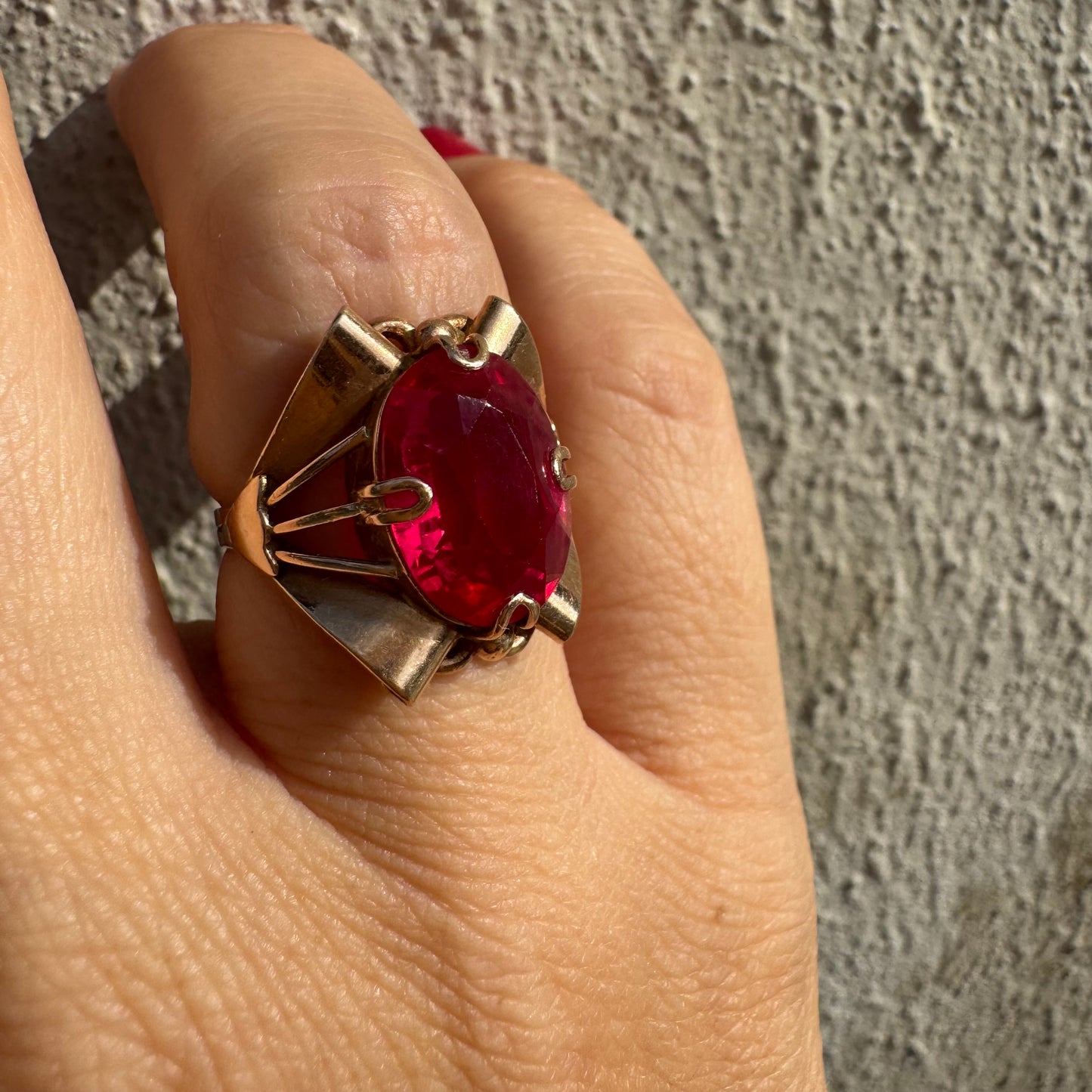 טבעת זהב 14 קראט משובצת אבן אובלית גדולה בצבע אדום חי במסגרת גאומטרית מיוחדת.