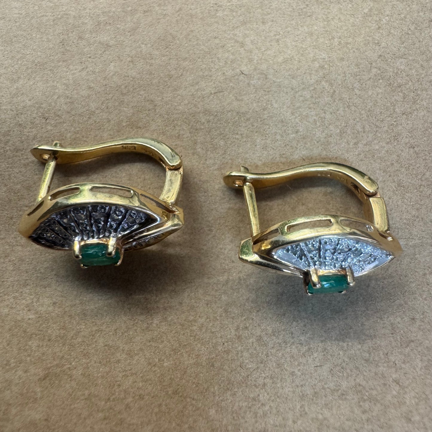 עגילים צמודים לאוזן, זהב צהוב 14 קראט, משובצים אמרלד במרכז, וסביבן פיתוחים משובצים יהלומים, שמעניקים מראה של ניצוץ רך ואלגנטי