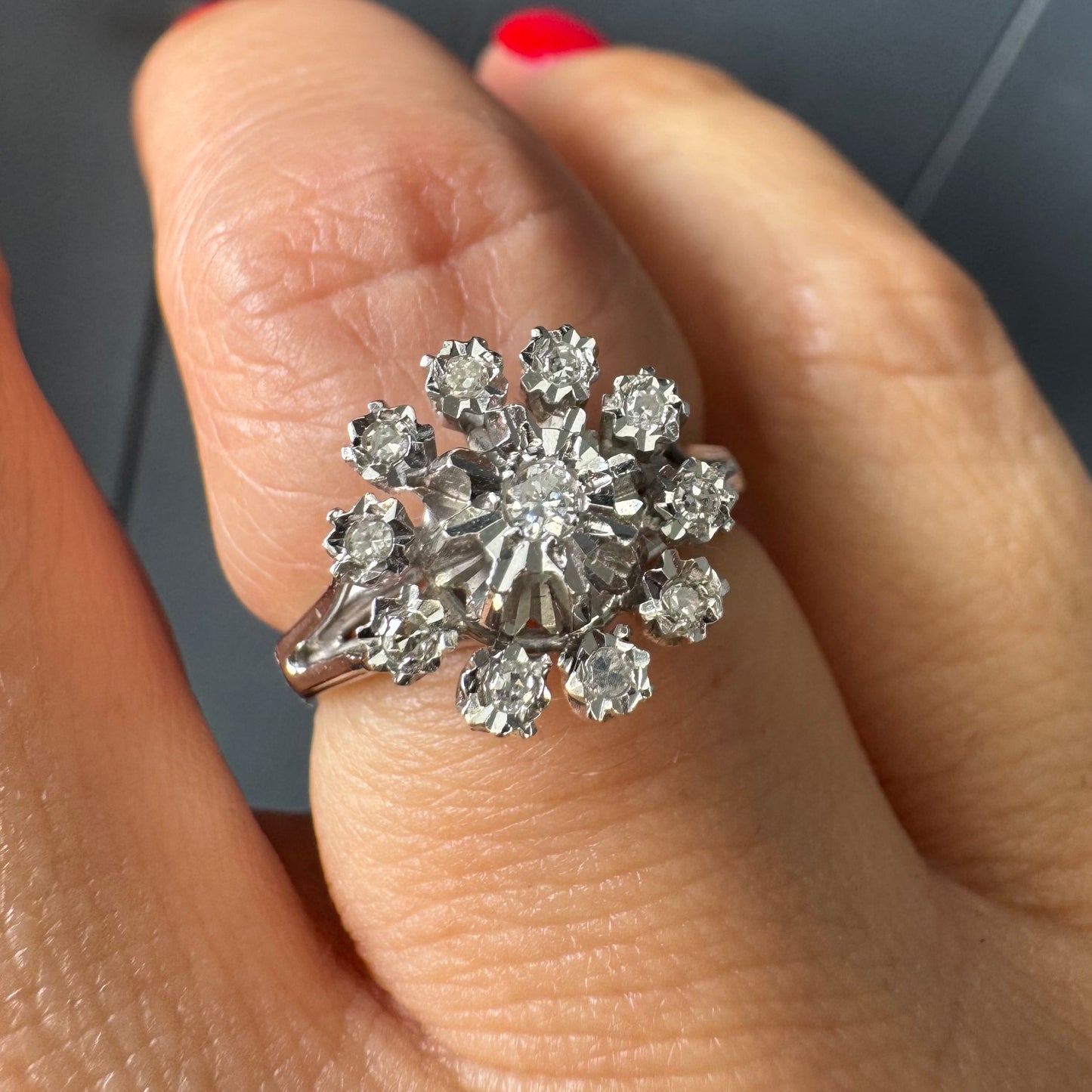 טבעת זהב 18 קראט משובצת יהלום מרכזי מוקף יהלומים נוספים בעיצוב פרח סימטרי ומרשים