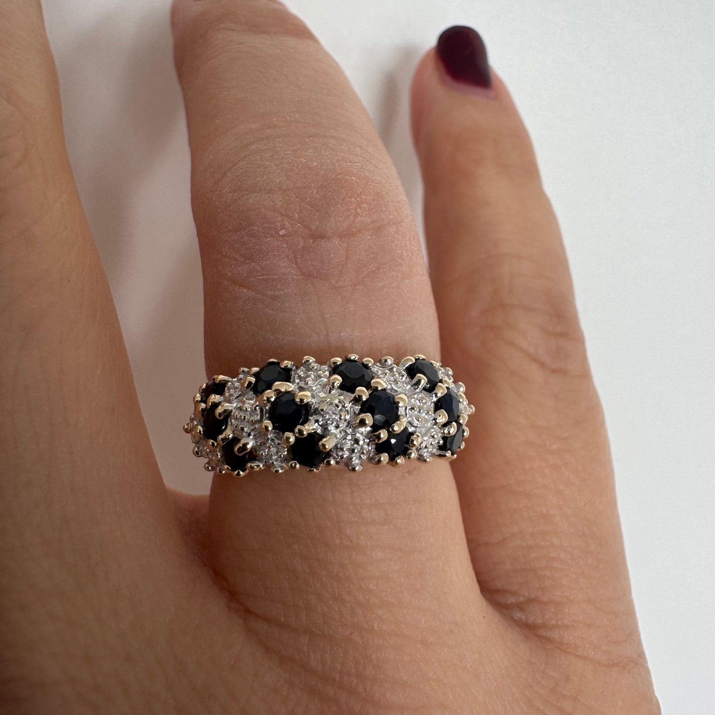 טבעת זהב צהוב 10 קראט משובצת אבני ספיר כהות ויהלומים בעיצוב קלאסי ורומנטי.