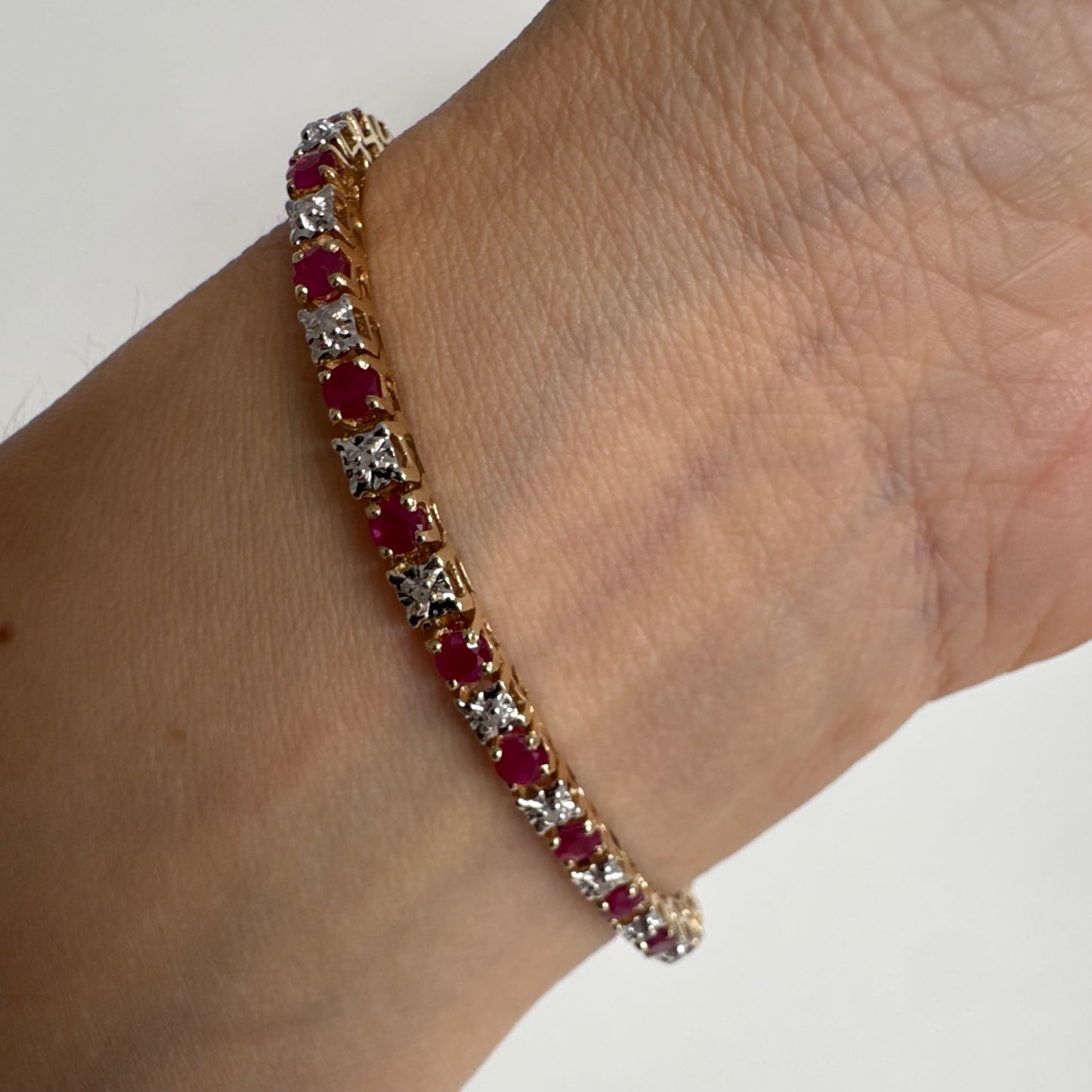צמיד זהב צהוב 10 קראט משובץ אבני רובי בגוון אדום עמוק וביניהן יהלומים לבנים מנצנצים.