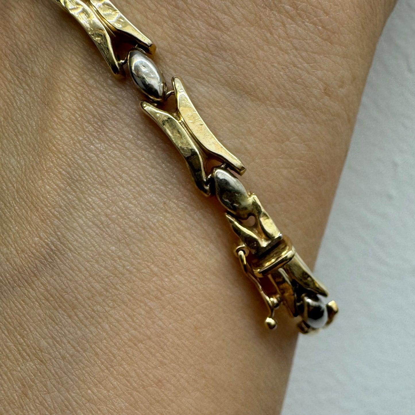 צמיד זהב צהוב וזהב לבן 14 קראט בעיצוב גאומטרי מיוחד, עם חיבורים בצורת X מזהב צהוב ושיבוצים מבריקים בזהב לבן