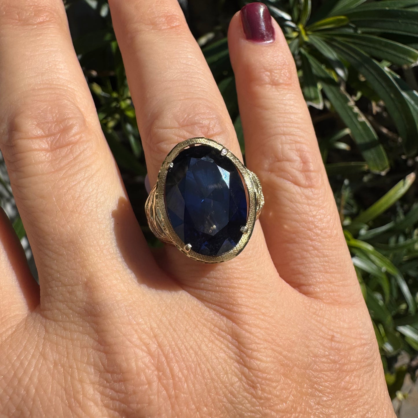 14K gold ring set with a deep navy-blue oval Sapphire in a dramatic openwork setting