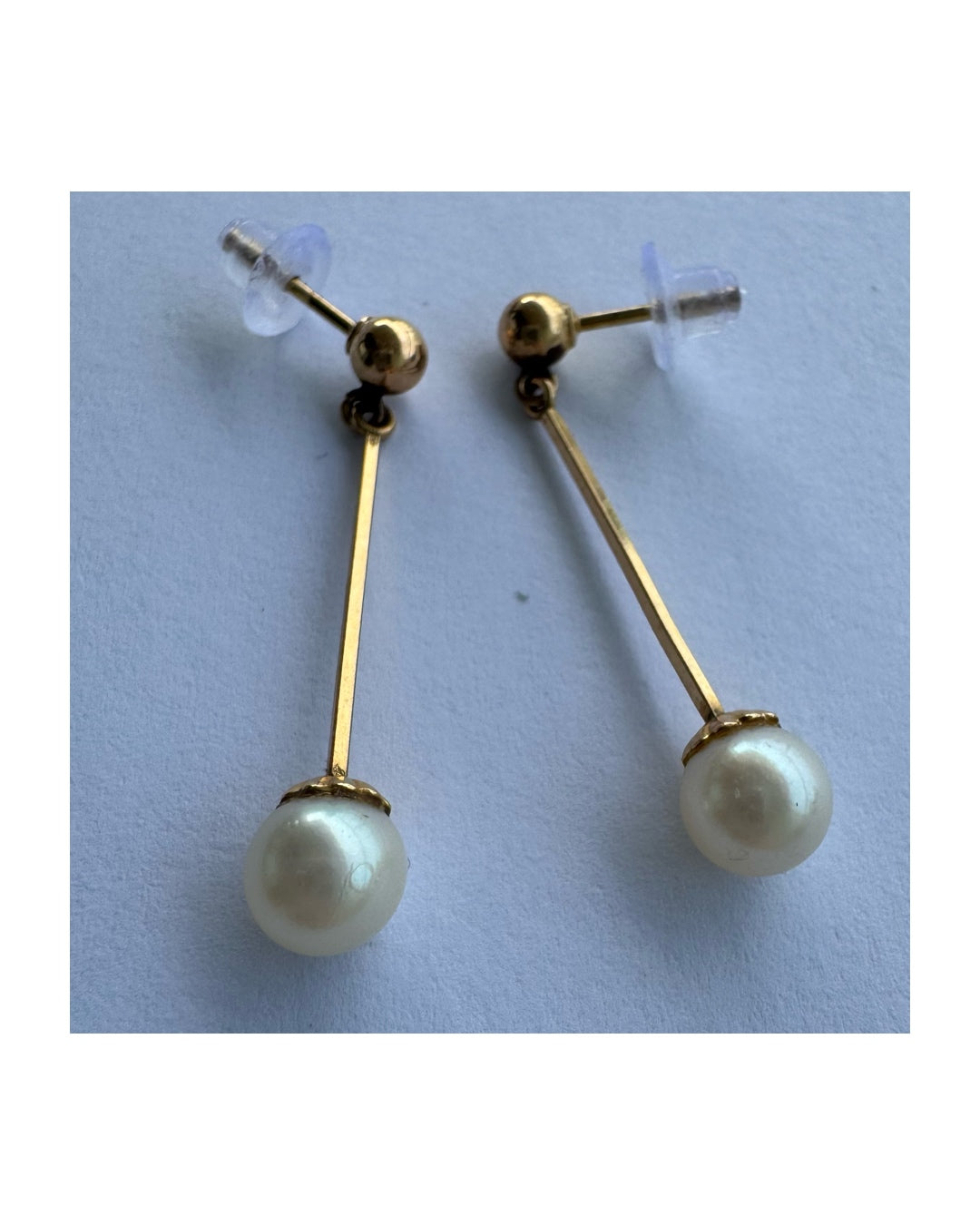 עגילי זהב 14 קראט בעיצוב תלוי ועדין, עם פנינה עגולה בקצה.