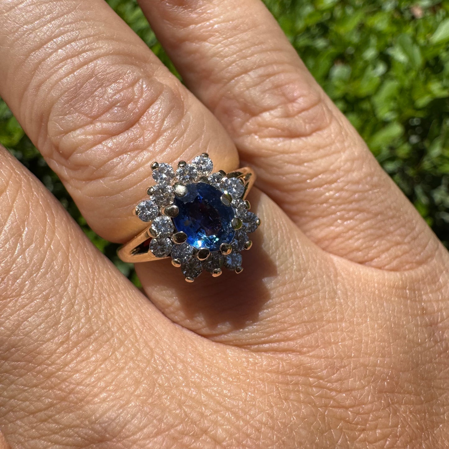 טבעת זהב צהוב 14 קראט משובצת אבן ספיר כחולה במרכז, מוקפת בהילה נוצצת של יהלומים.