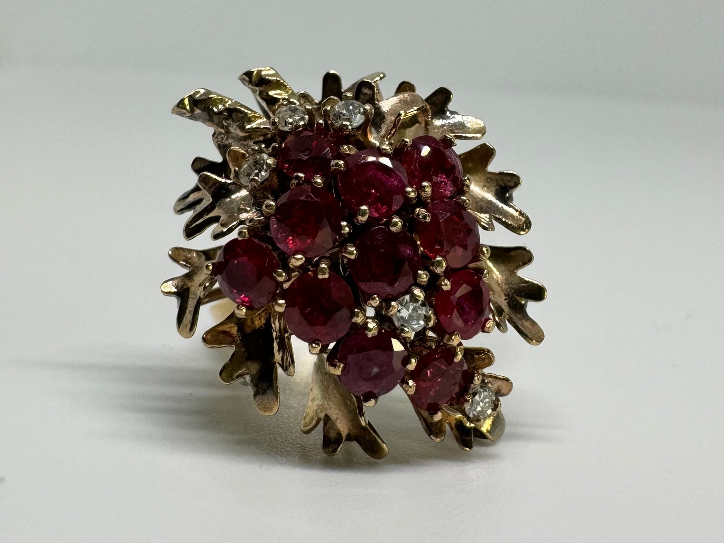 14K gold ring set with a vibrant cluster of deep red rubies and sparkling diamonds.
