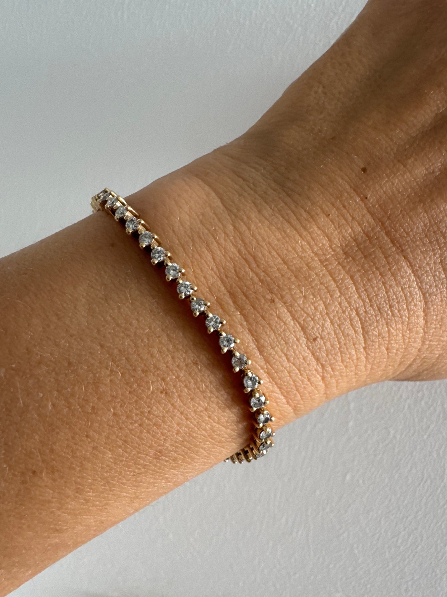 צמיד טניס קלאסי מזהב 14 קראט, משובץ שורה רציפה של יהלומים עגולים המעניקים ברק עדין ואלגנטי.