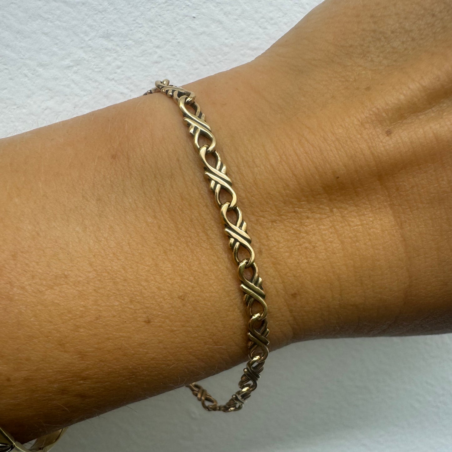 צמיד זהב צהוב 14 קראט עם חוליות שזורות בעיצוב שזירה ופיתול, וסוגר מסוג לובסטר.