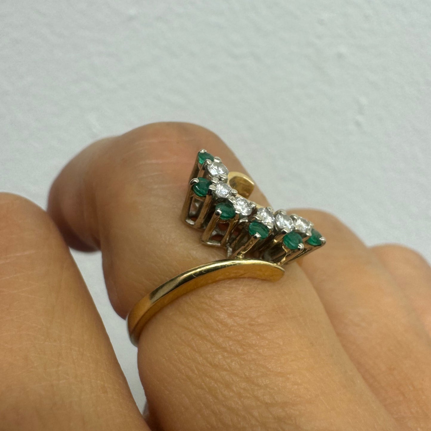 14K gold open ring featuring a delicate swirl set with Emeralds and brilliant-cut Diamonds