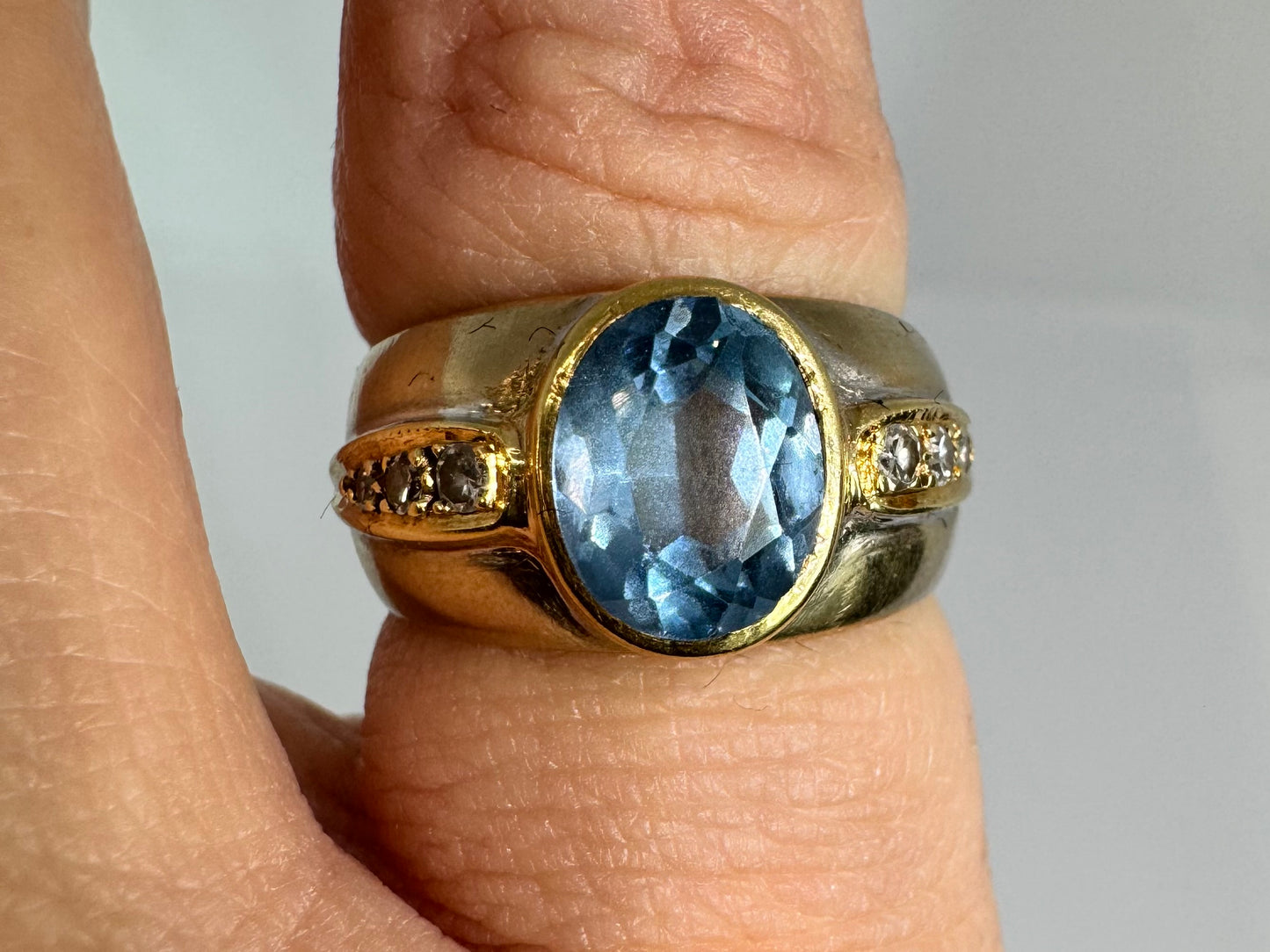 14K gold ring set with a luminous Blue Topaz at its center, accented by delicate side Diamonds