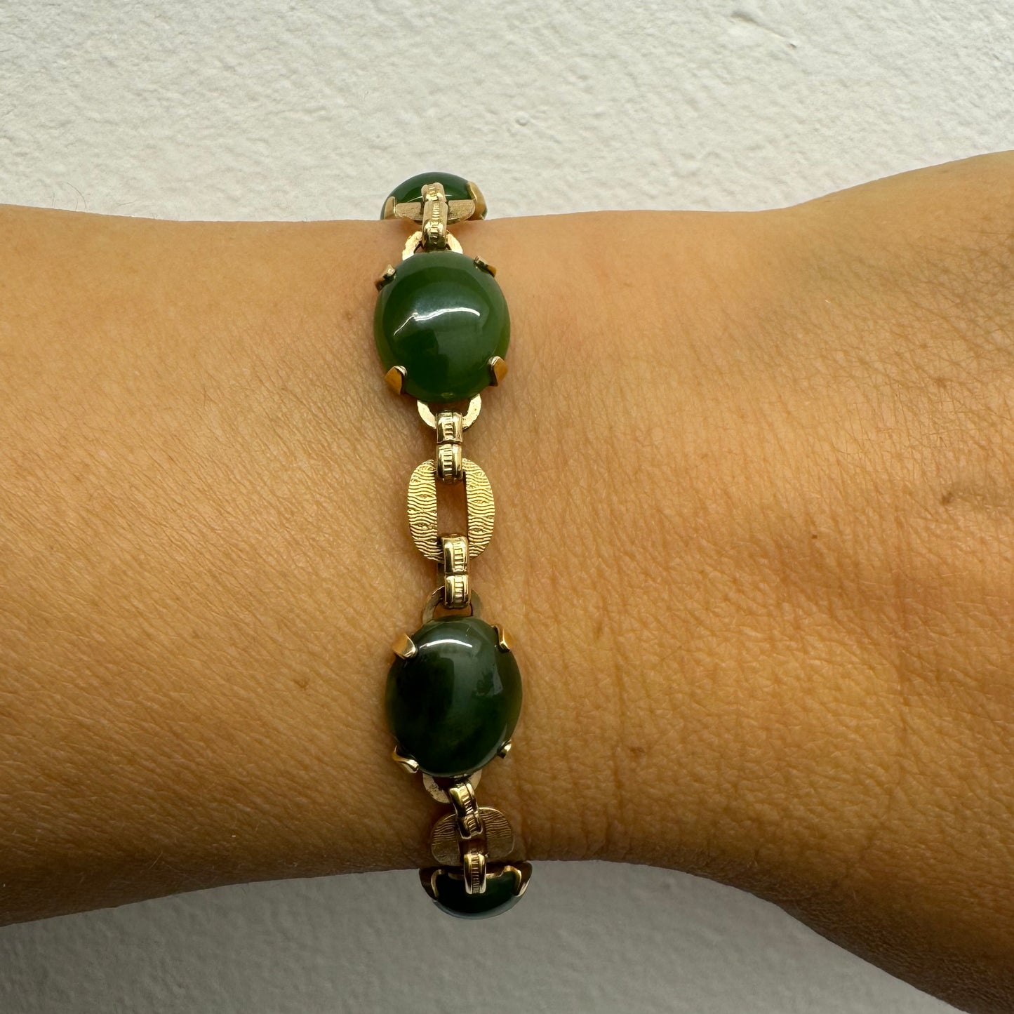 צמיד זהב צהוב 14 קראט משובץ באבני ג’ייד ירוקות בחיתוך קבושון (cabochon) בעיצוב אליפטי, המחוברות ביניהן בחוליות זהב עם טקסטורה מעניינת.