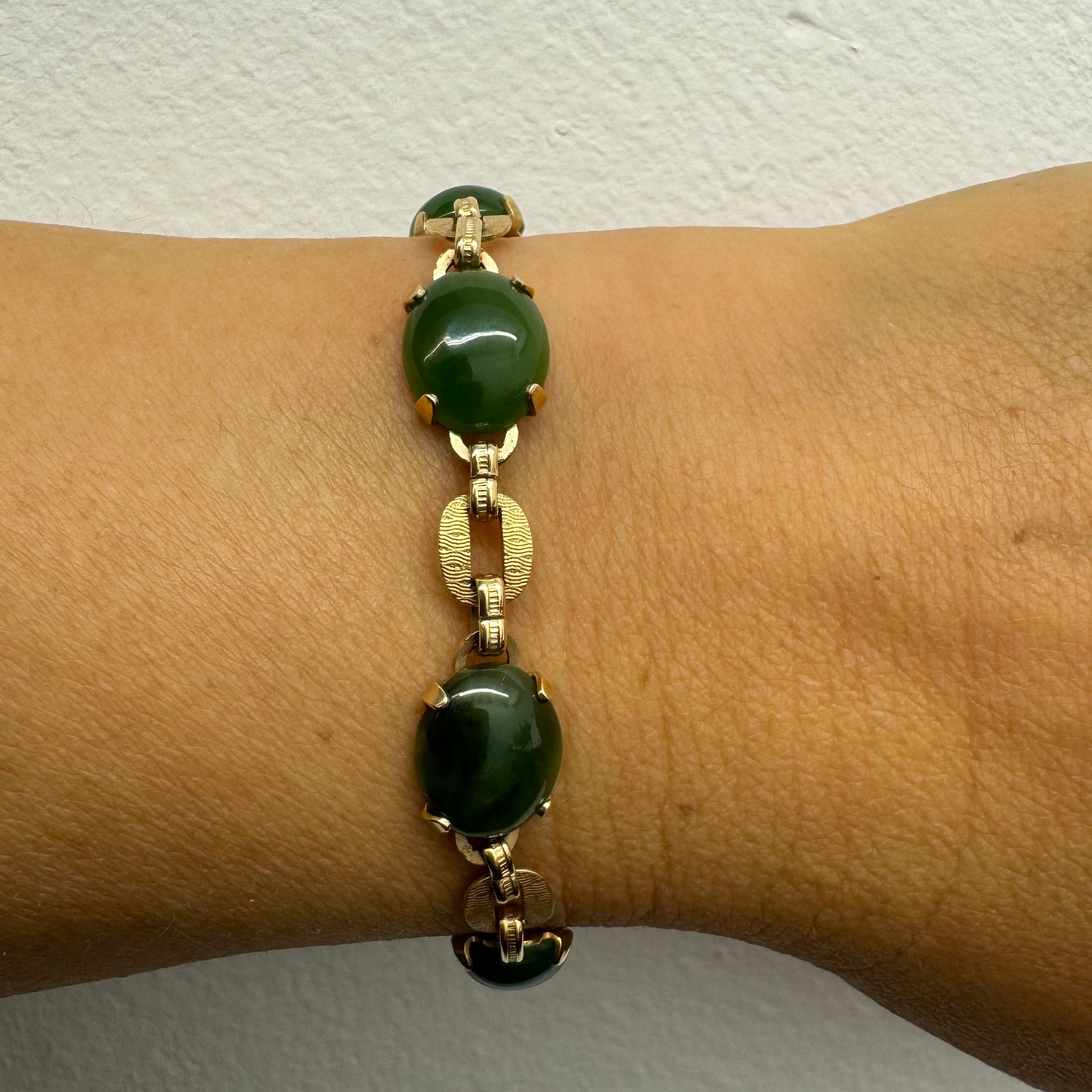 צמיד זהב צהוב 14 קראט משובץ באבני ג’ייד ירוקות בחיתוך קבושון (cabochon) בעיצוב אליפטי, המחוברות ביניהן בחוליות זהב עם טקסטורה מעניינת.