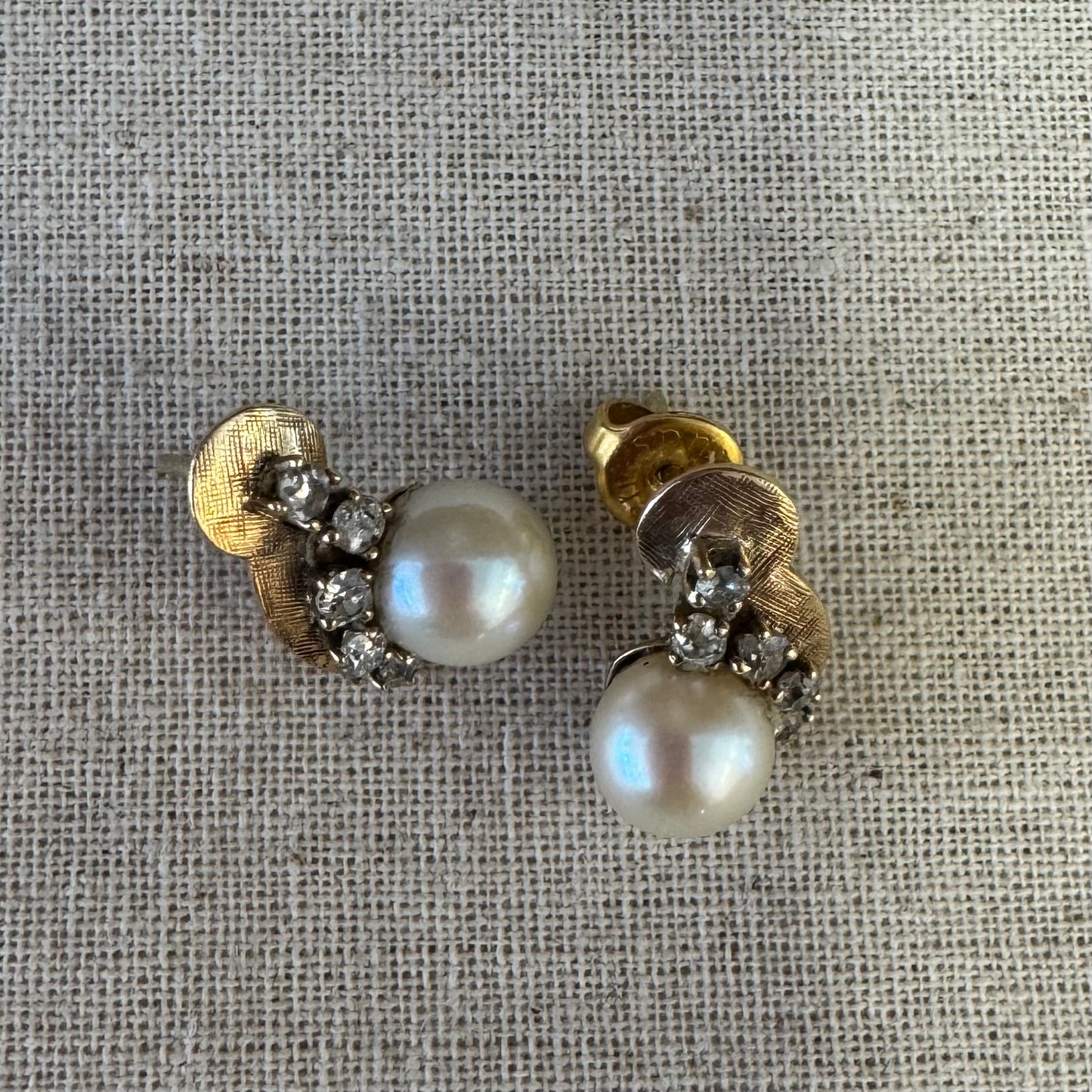 עגילי זהב צהוב 14 קראט, צמודים לאוזן, עשויים זהב בגימור טקסטורלי ומשובצים פנינה עגולה ובשורת יהלומים קטנים בחיתוך עתיק.