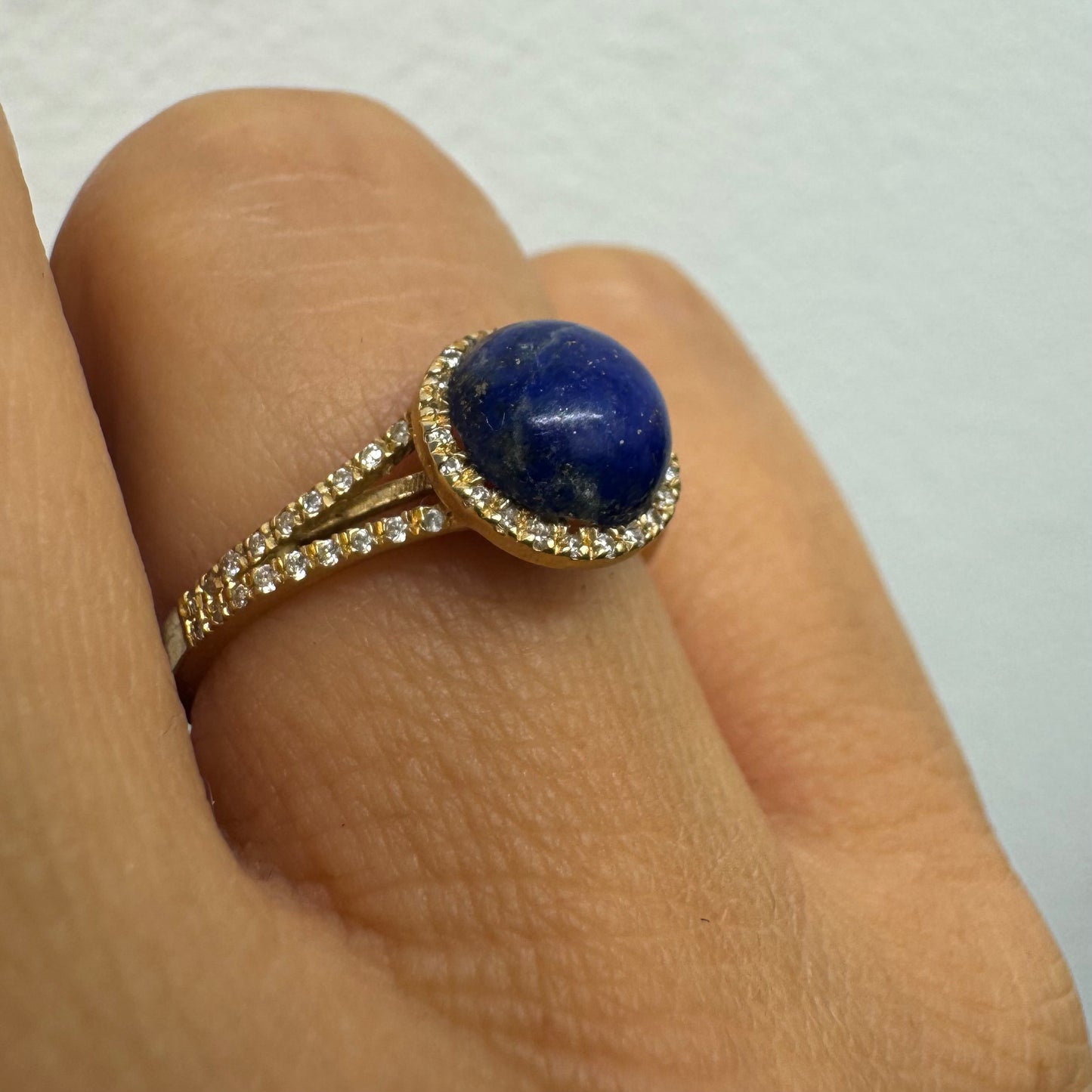 14K gold ring set with a round Lapis Lazuli gemstone, surrounded by a delicate halo of sparkling Diamonds.