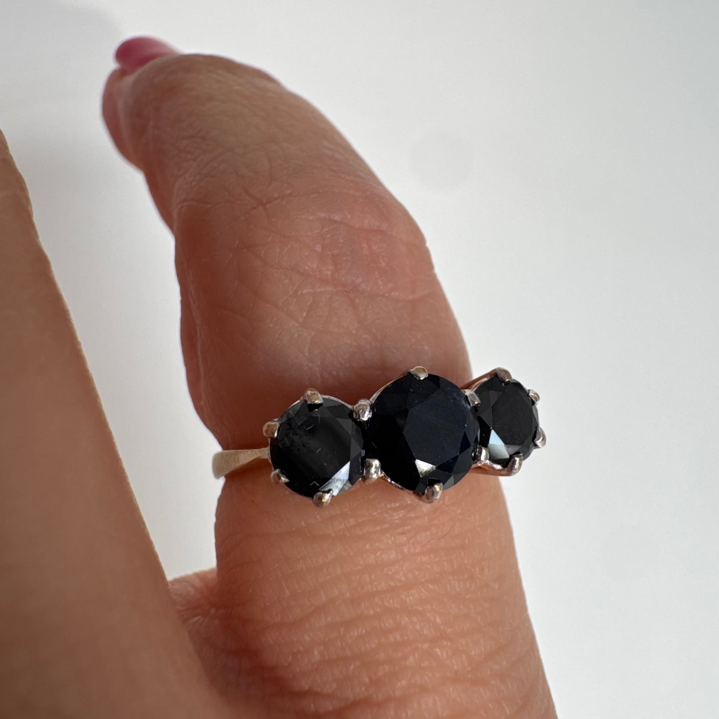 טבעת זהב 10 קראט משובצת שלוש אבני ספיר בצבע כחול כהה בחיתוך עגול, בעיצוב קלאסי עם נוכחות עמוקה ואלגנטית.